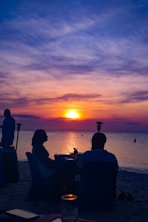Couple watches a vibrant sunset on a beach.