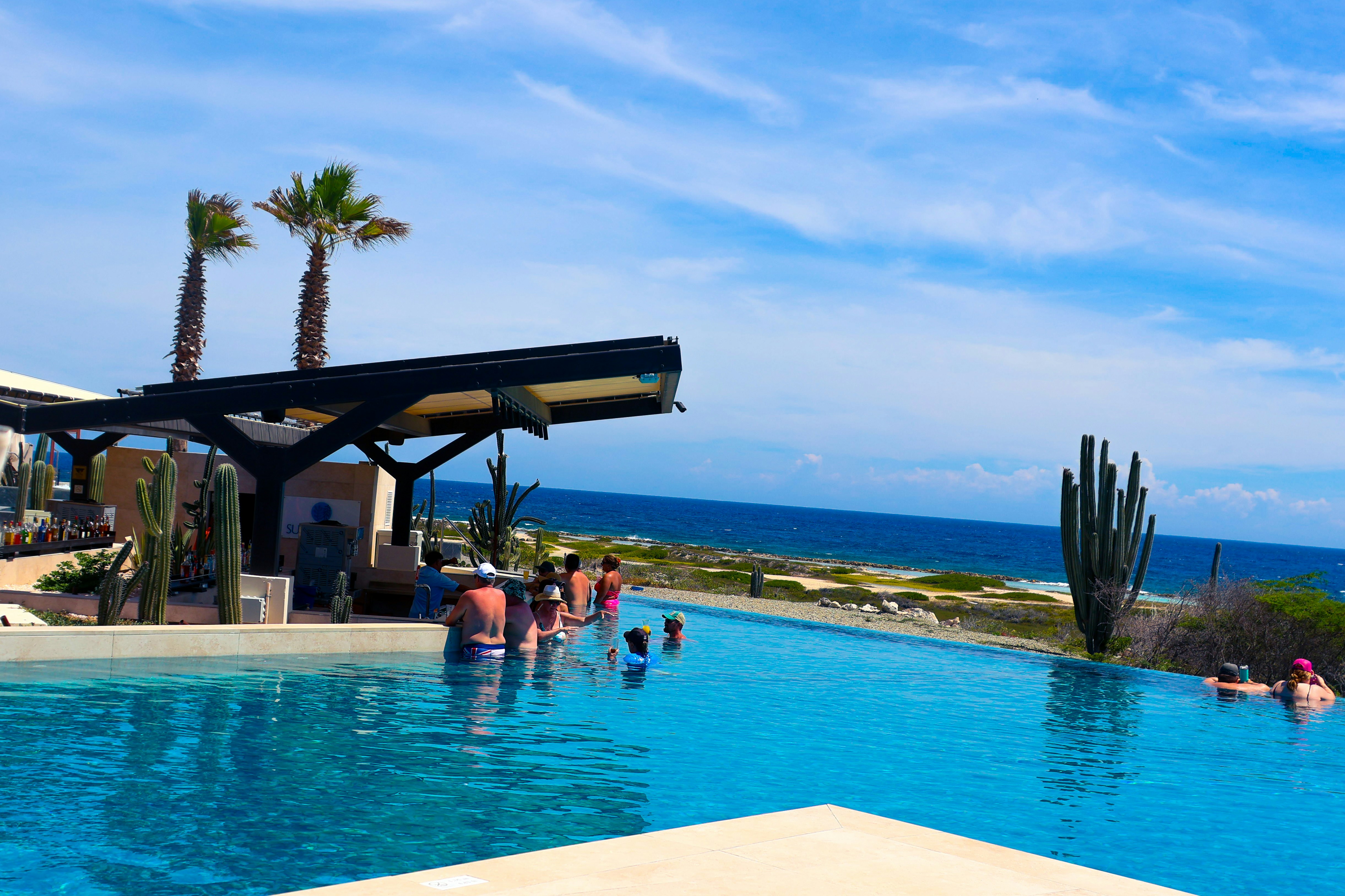 People relax in an infinity pool overlooking the ocean.