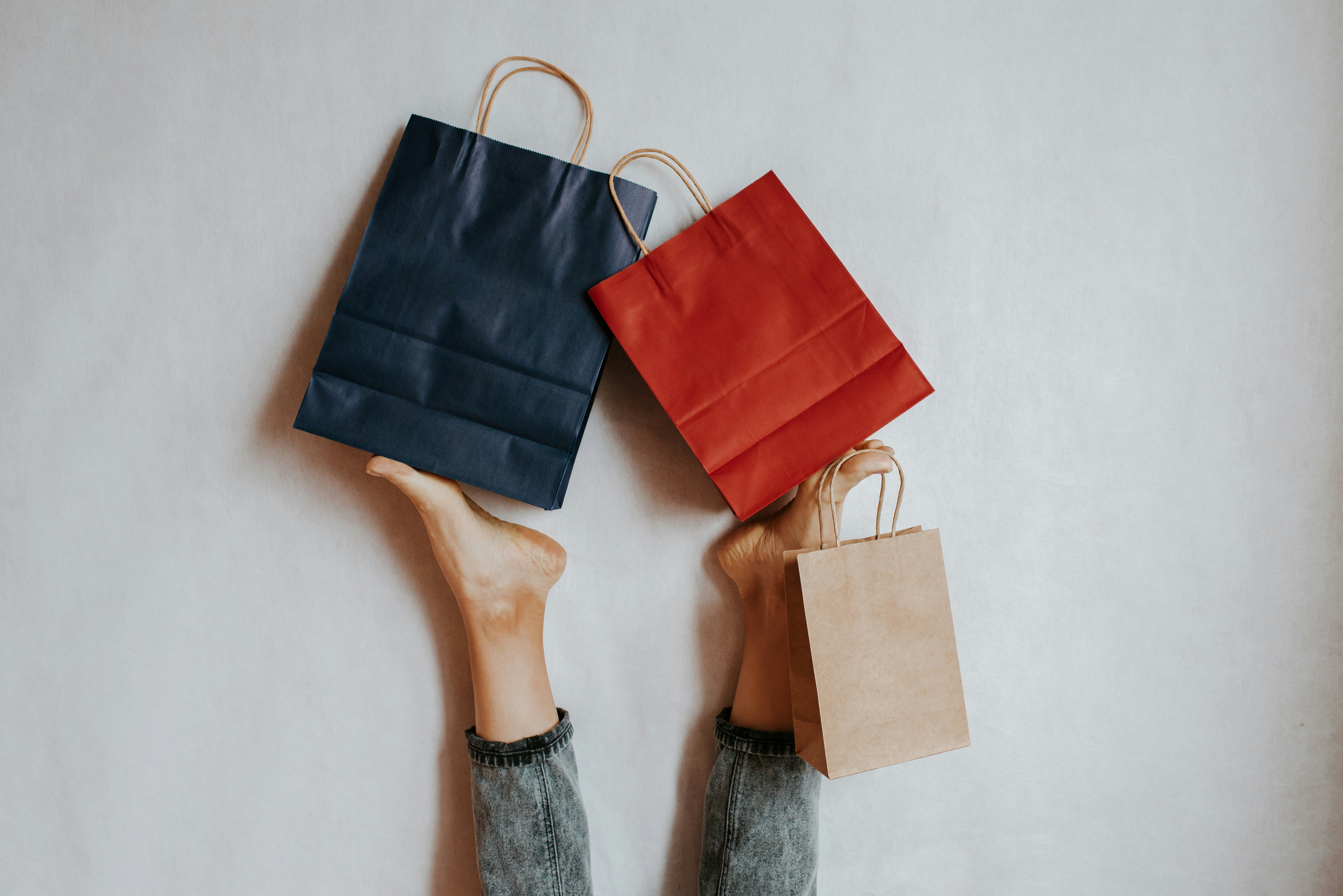 Happy woman holding on feet shopping package. Paper bag. Sale in store. Fashion shop creative advertisement. Customer buy present. Black friday sale. Holiday special offer, discount. Season deal