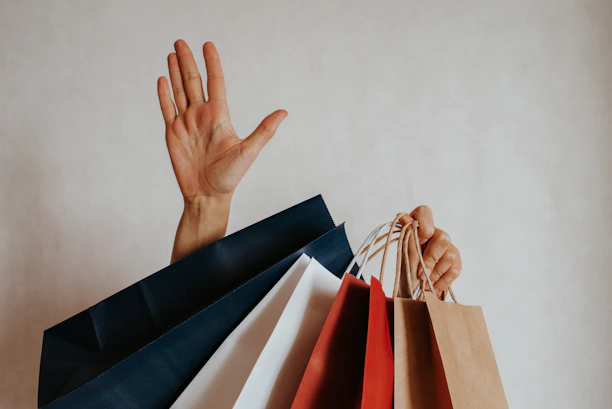 Person waving from behind shopping bags
