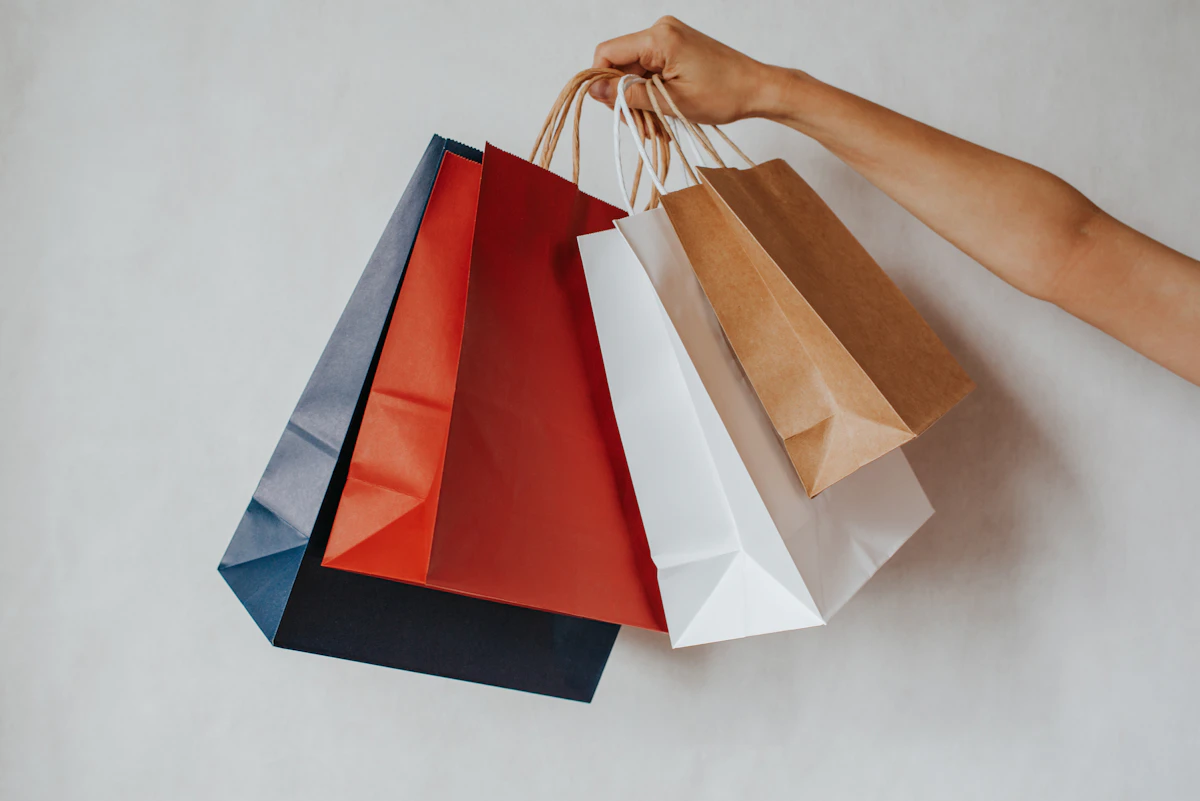 Hand holding red, white and kraft shopping bags