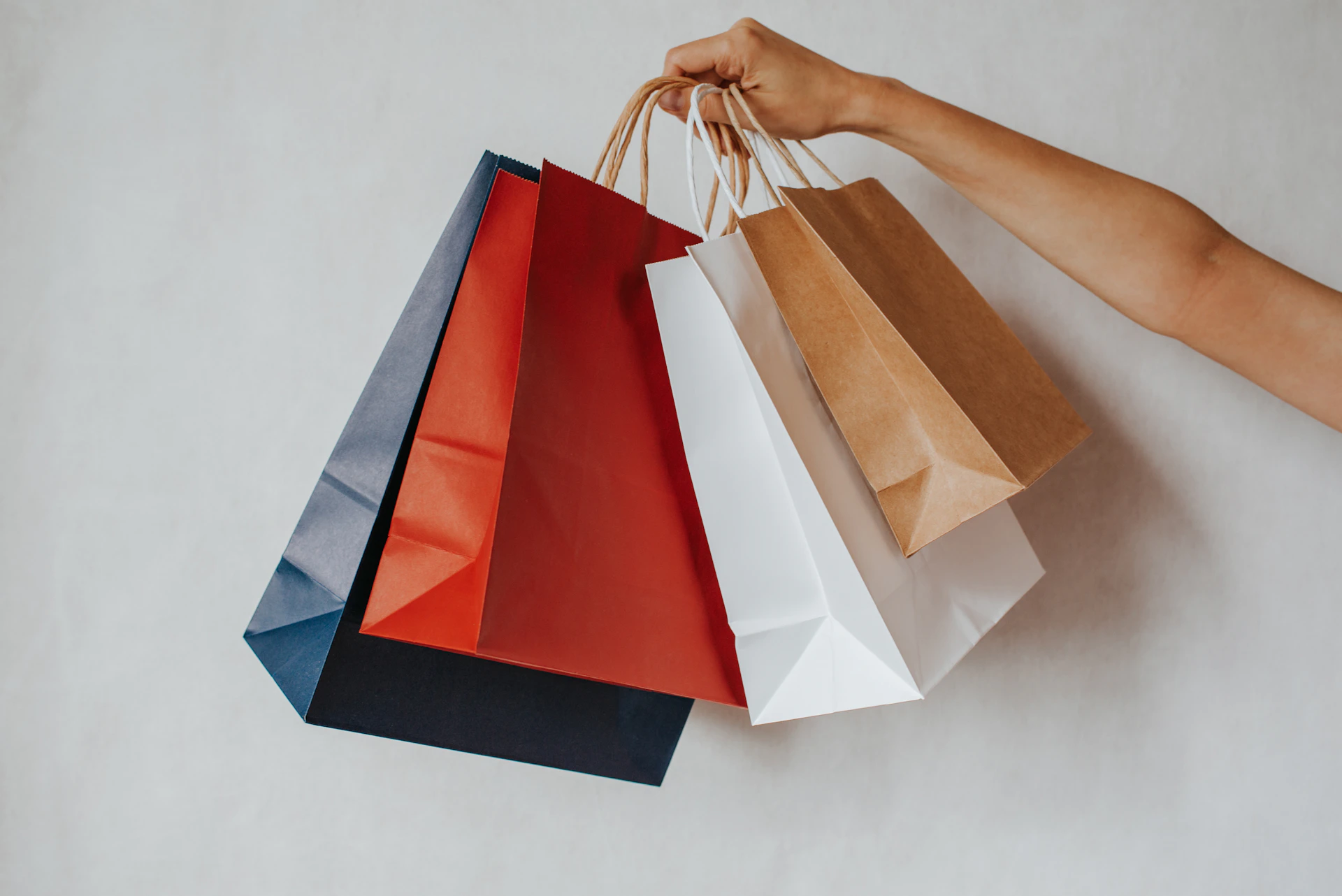 Hand holding colorful shopping bags against a white background