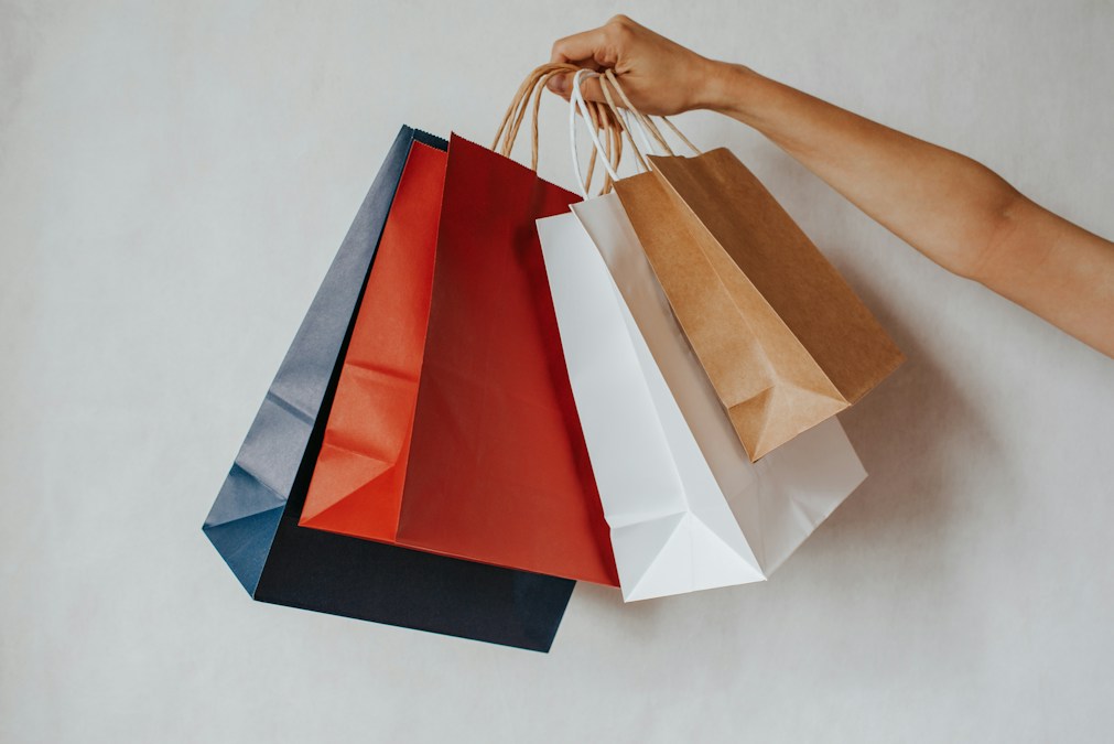 Main tenant des sacs de shopping en papier rouge, bleu, blanc et kraft : le Black Friday 2026 se tiendra le 27 novembre en Belgique