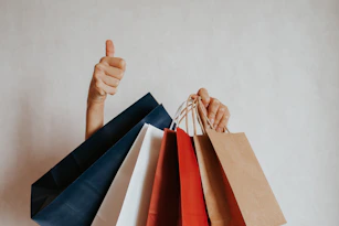 Person holding shopping bags with a thumbs up