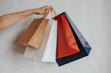 Hand holding colorful shopping bags against a light background