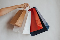 Hand holding colorful shopping bags against a light background