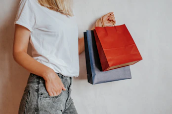 Woman holding shopping bags against a wall