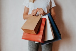 Woman holding shopping bags in front of white wall