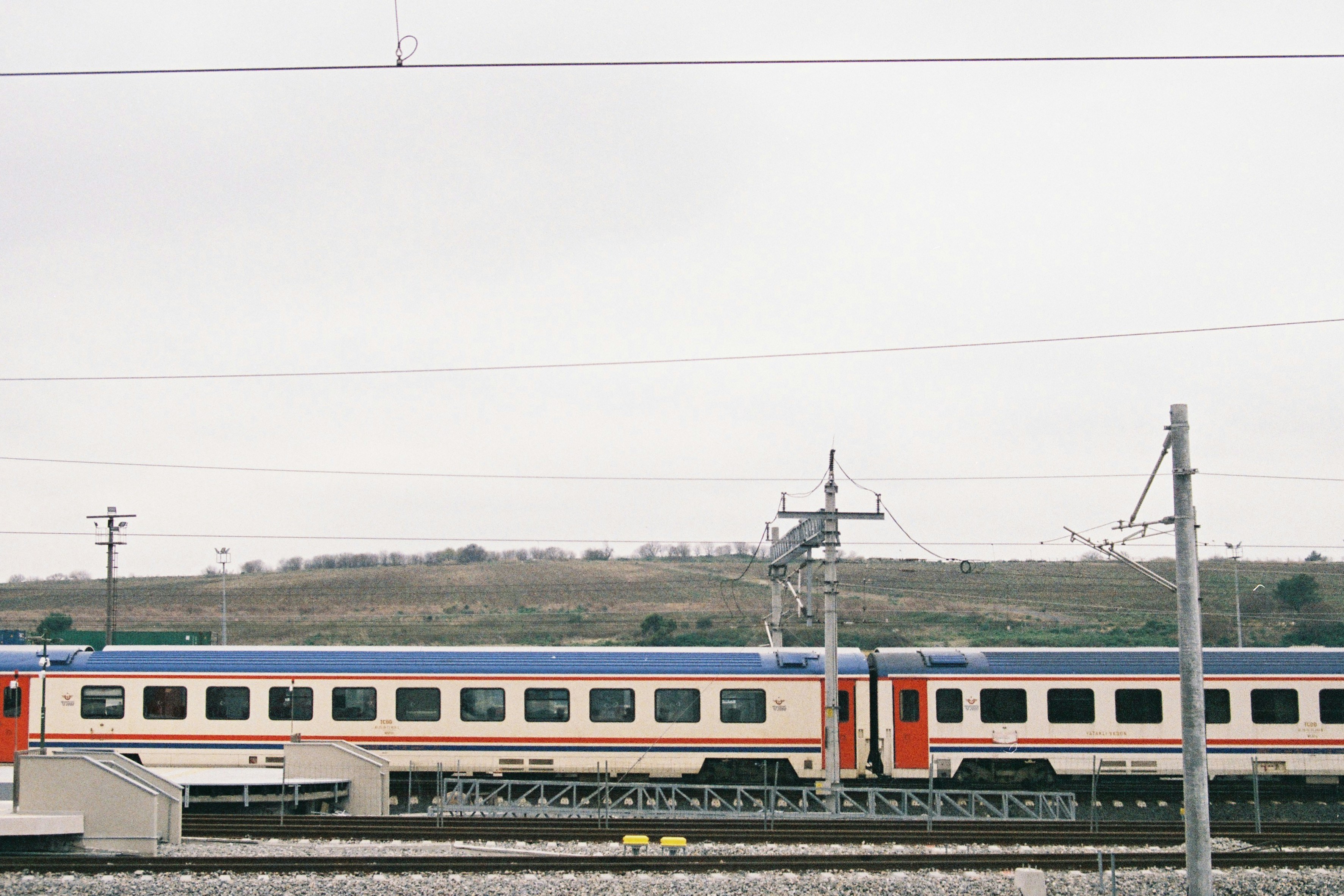 A passenger train with red doors travels on tracks.