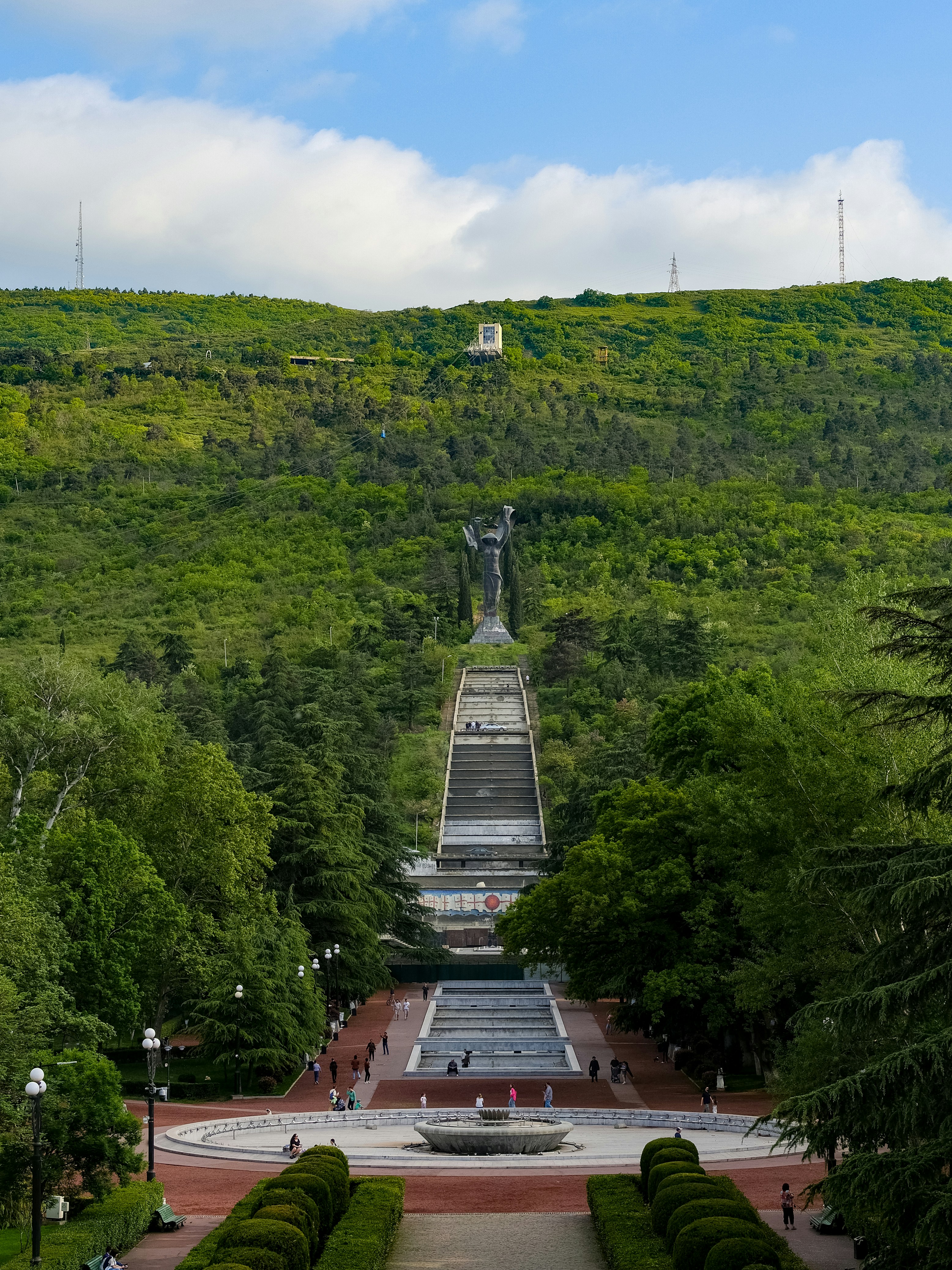 Monumental statue atop a long staircase on a hill.