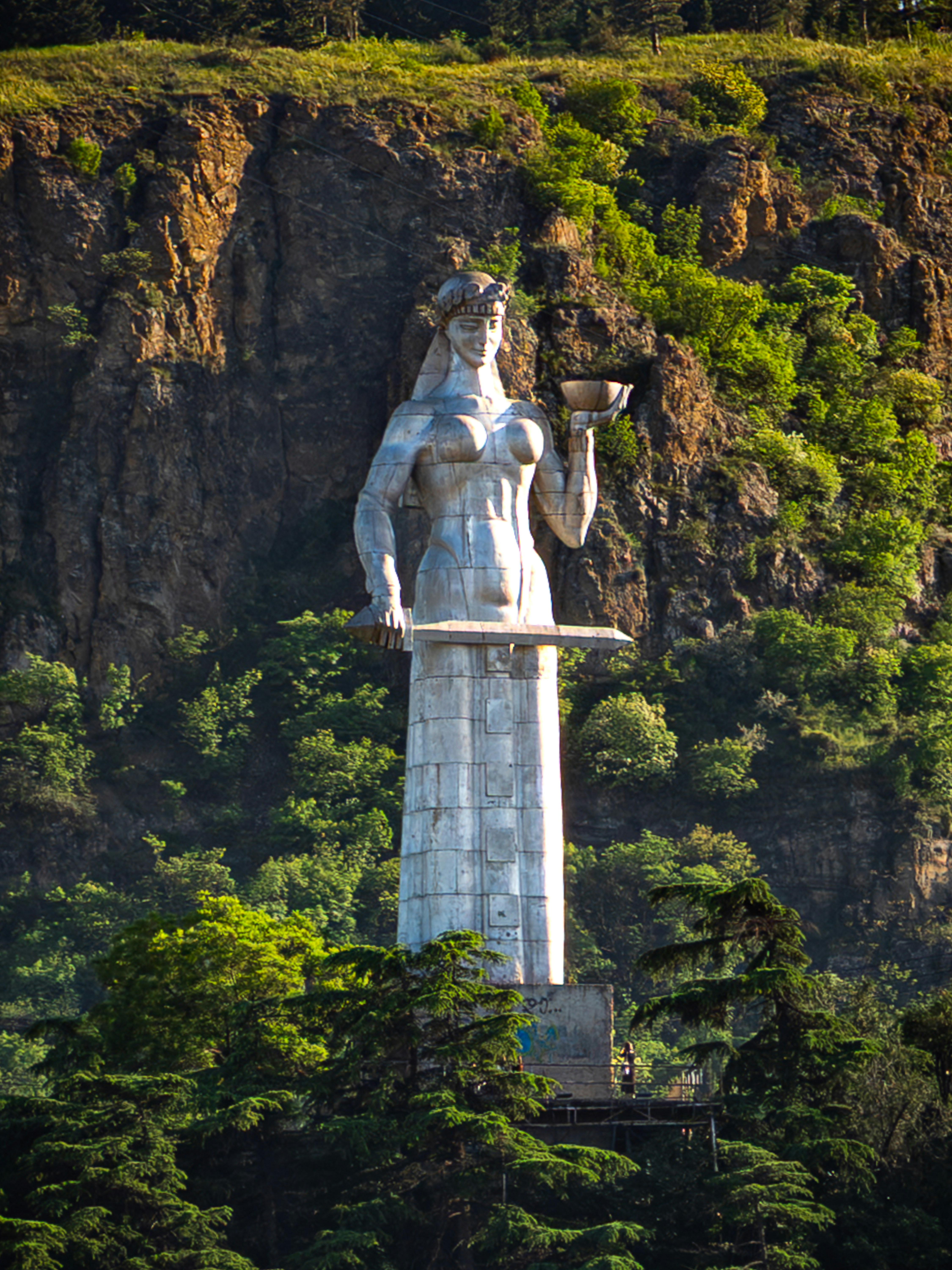 Monumental statue of a woman holding wine and sword.