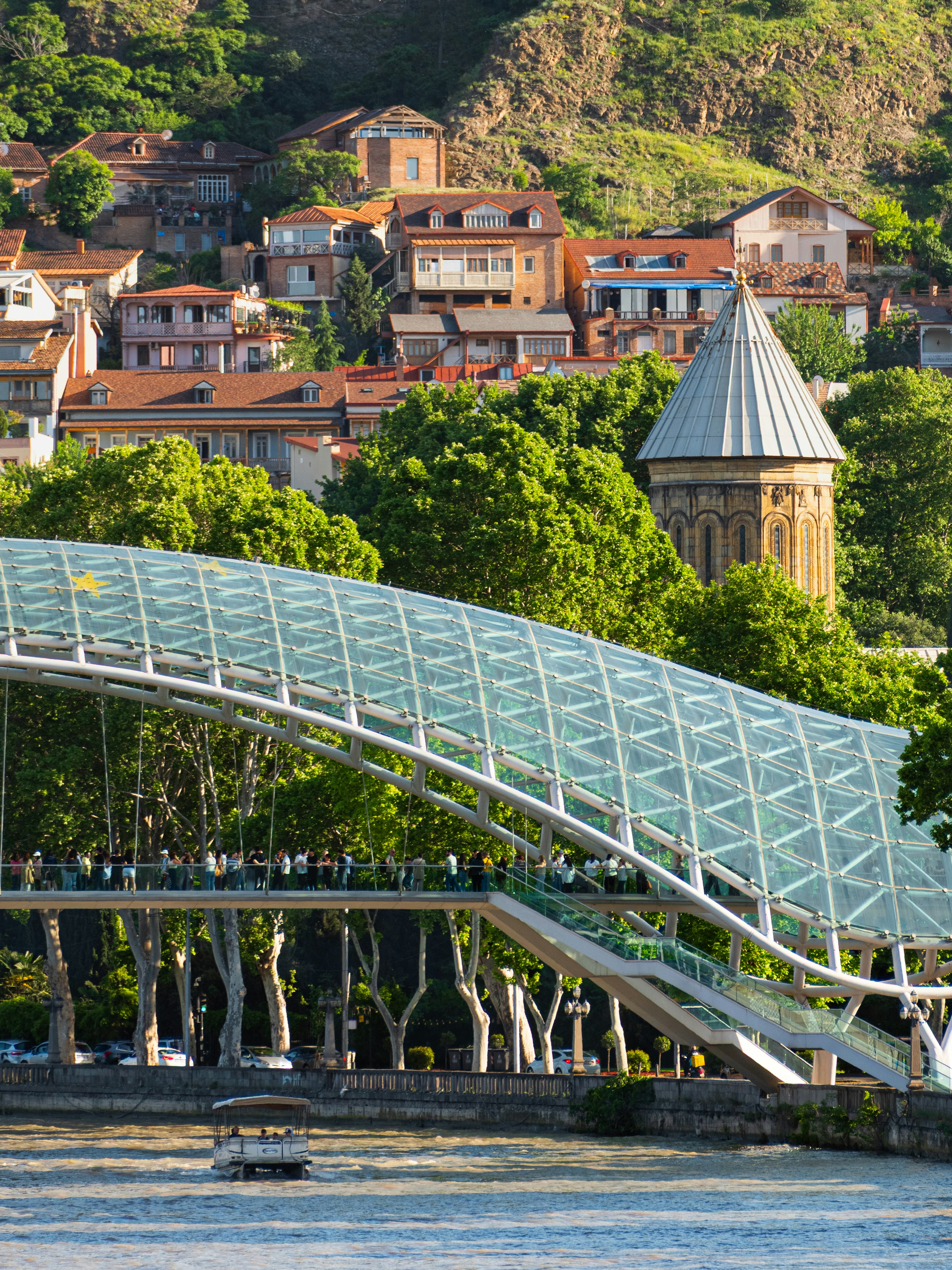 Modern glass bridge over river with old town background
