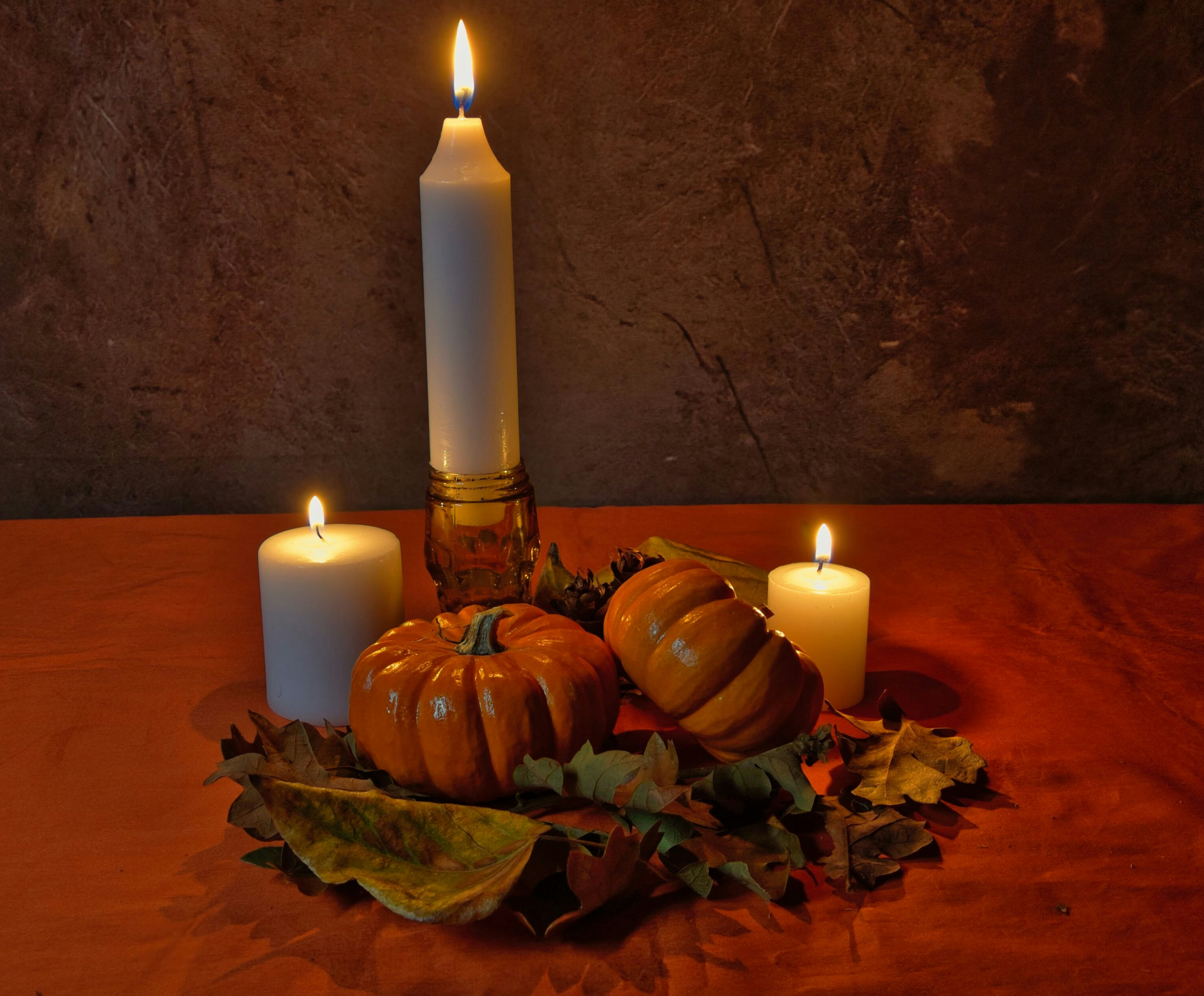 Kürbisse und brennende Kerzen auf Herbstlaub
