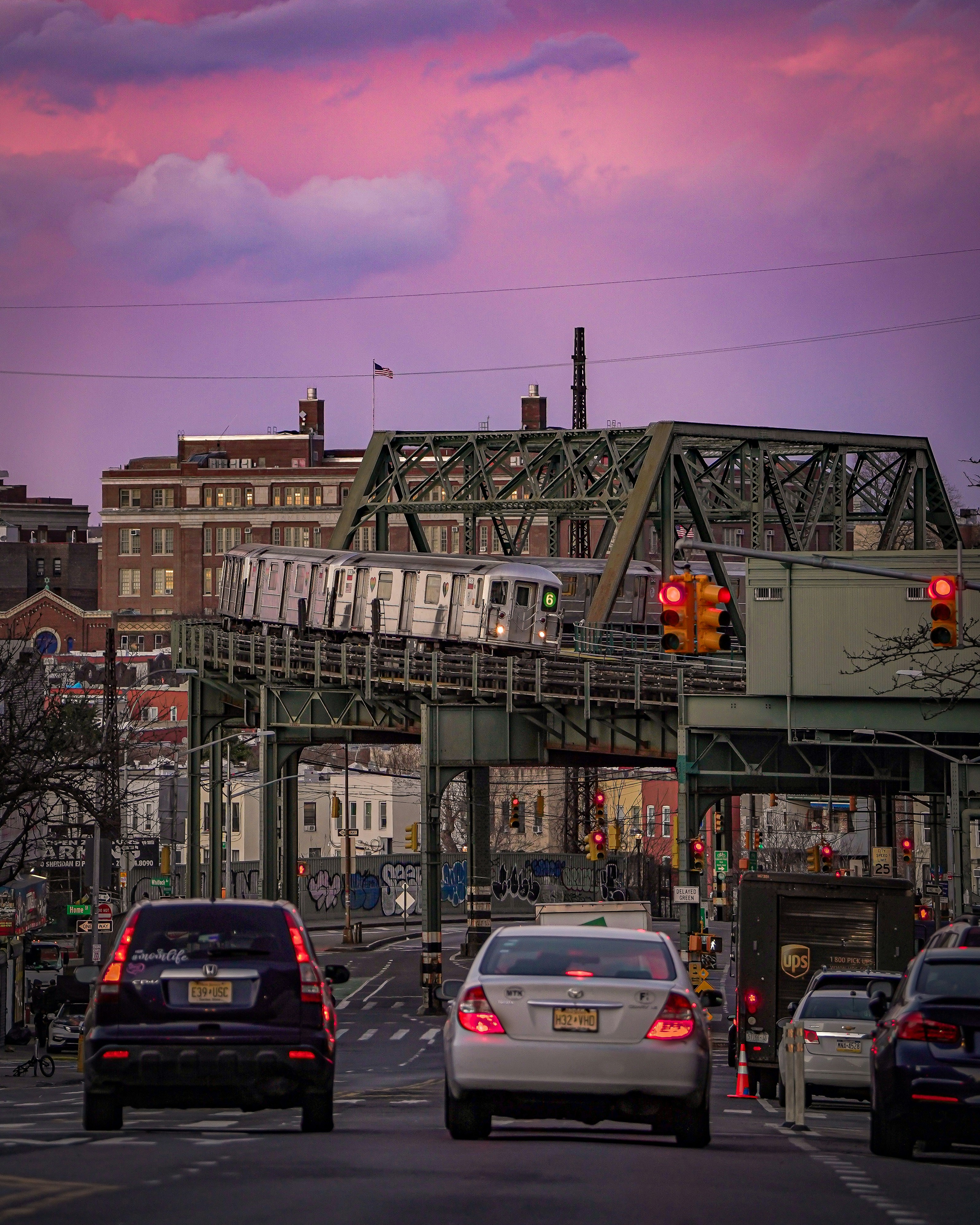 Train crosses bridge over busy street at sunset