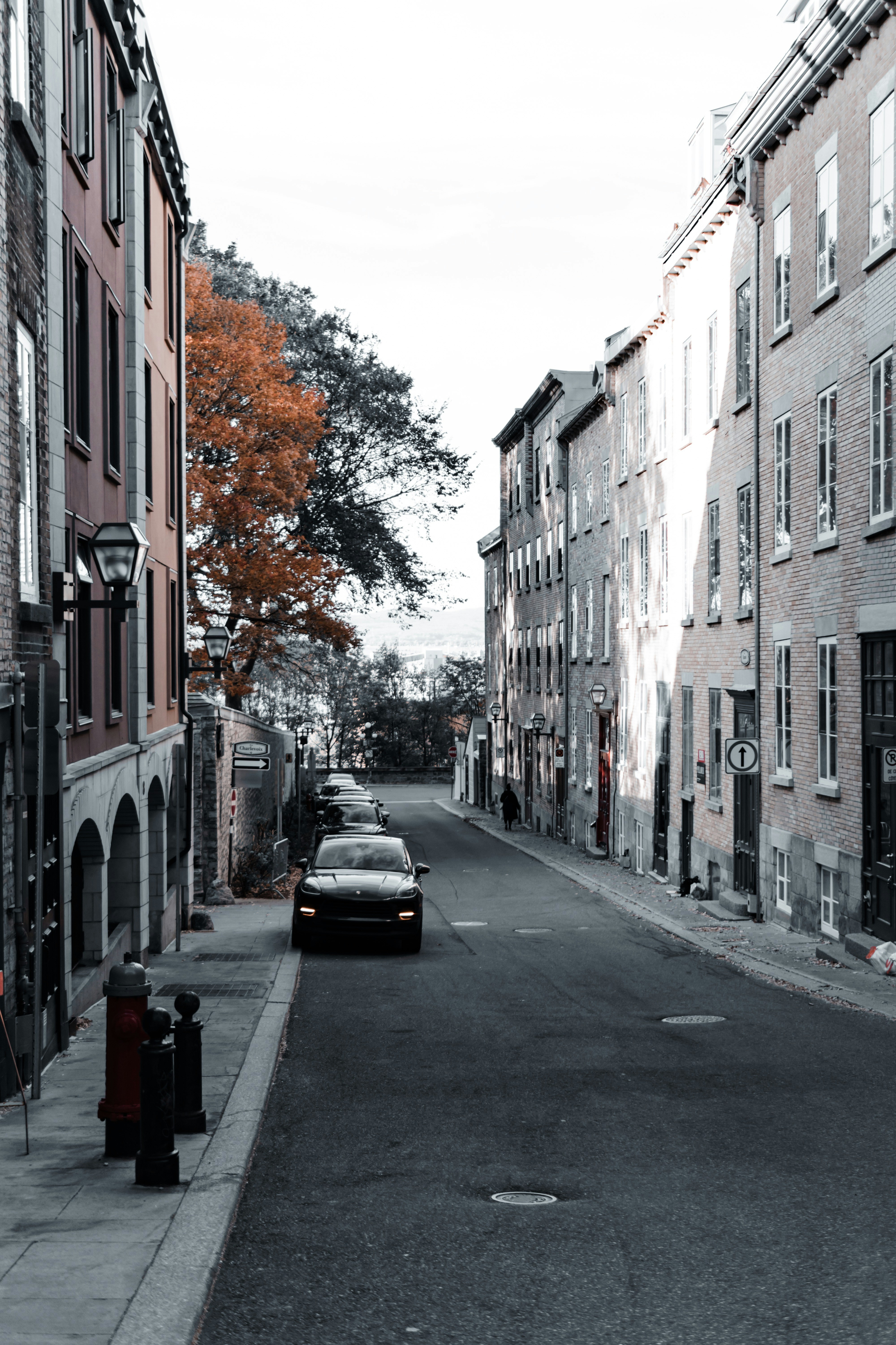 Car drives down a narrow cobblestone street.