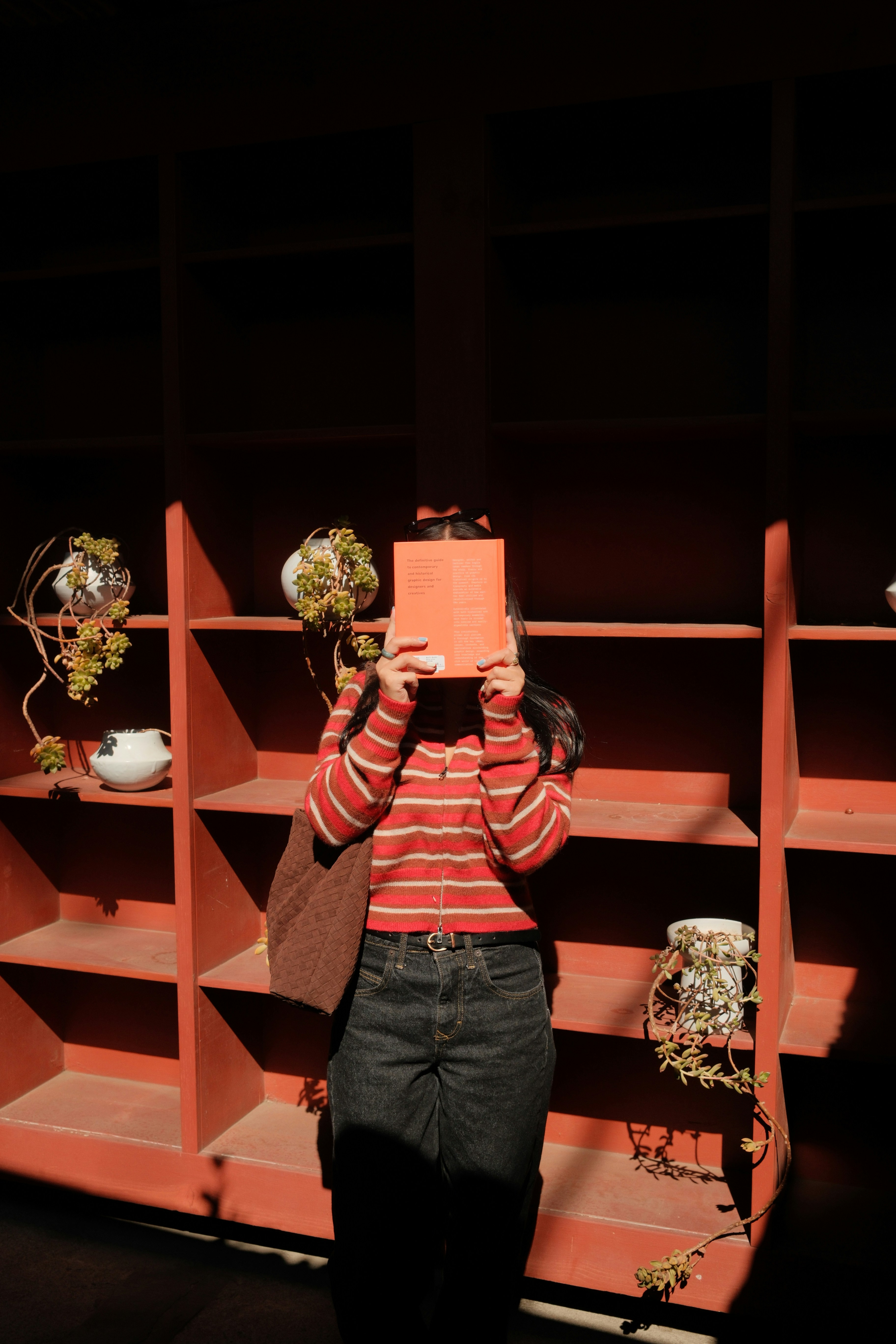 Person holds orange book in front of face