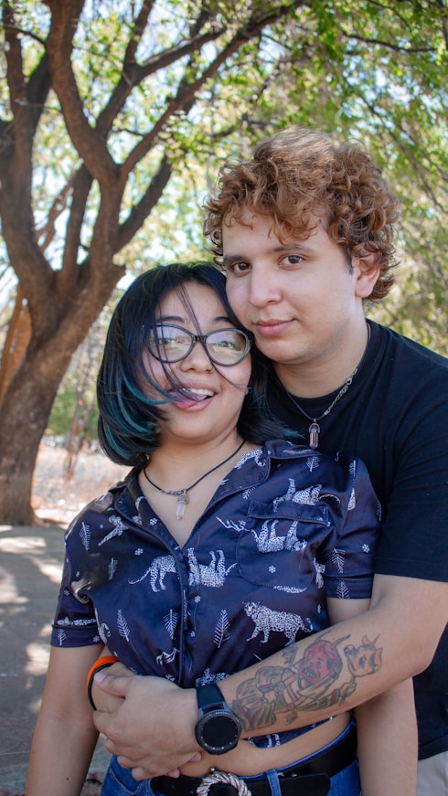 Young couple embracing outdoors under trees