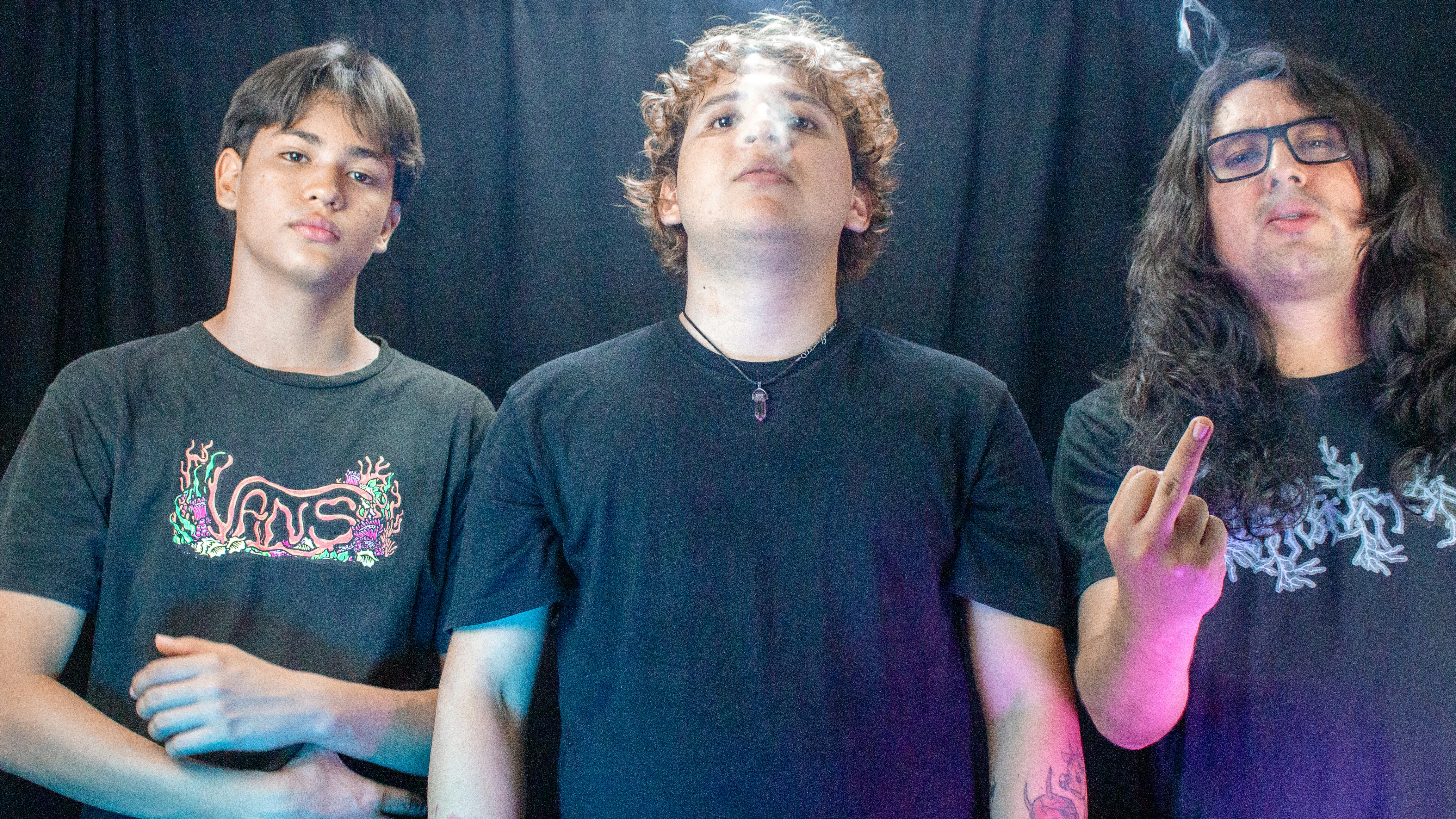 Three young men posing against a black backdrop