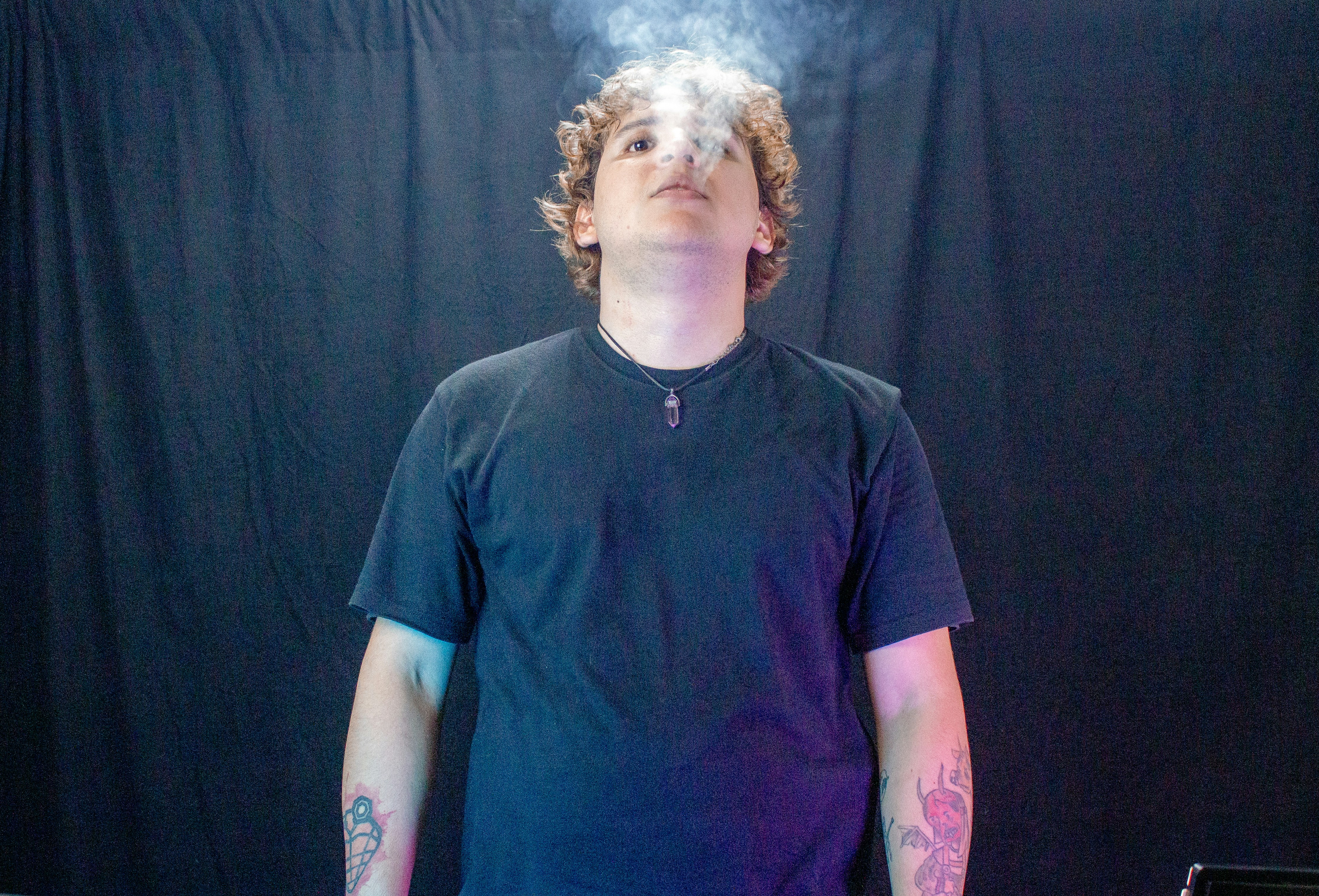 Young man exhaling smoke in front of dark background