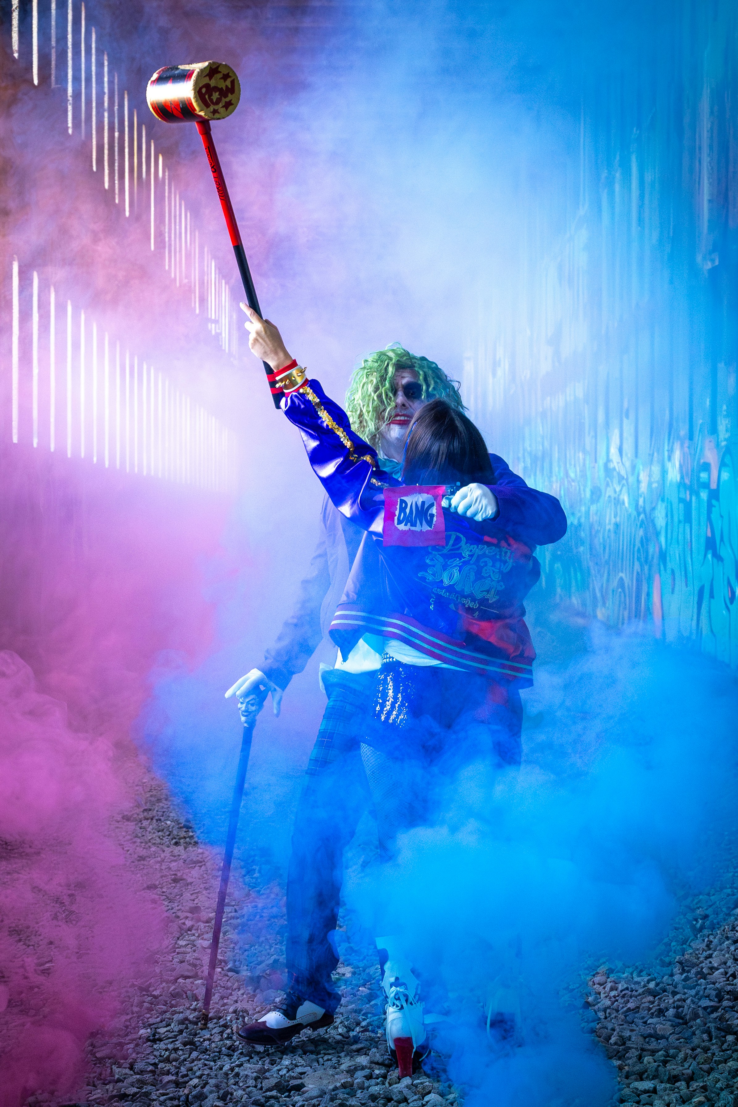 Two people in joker-like costumes with colorful smoke