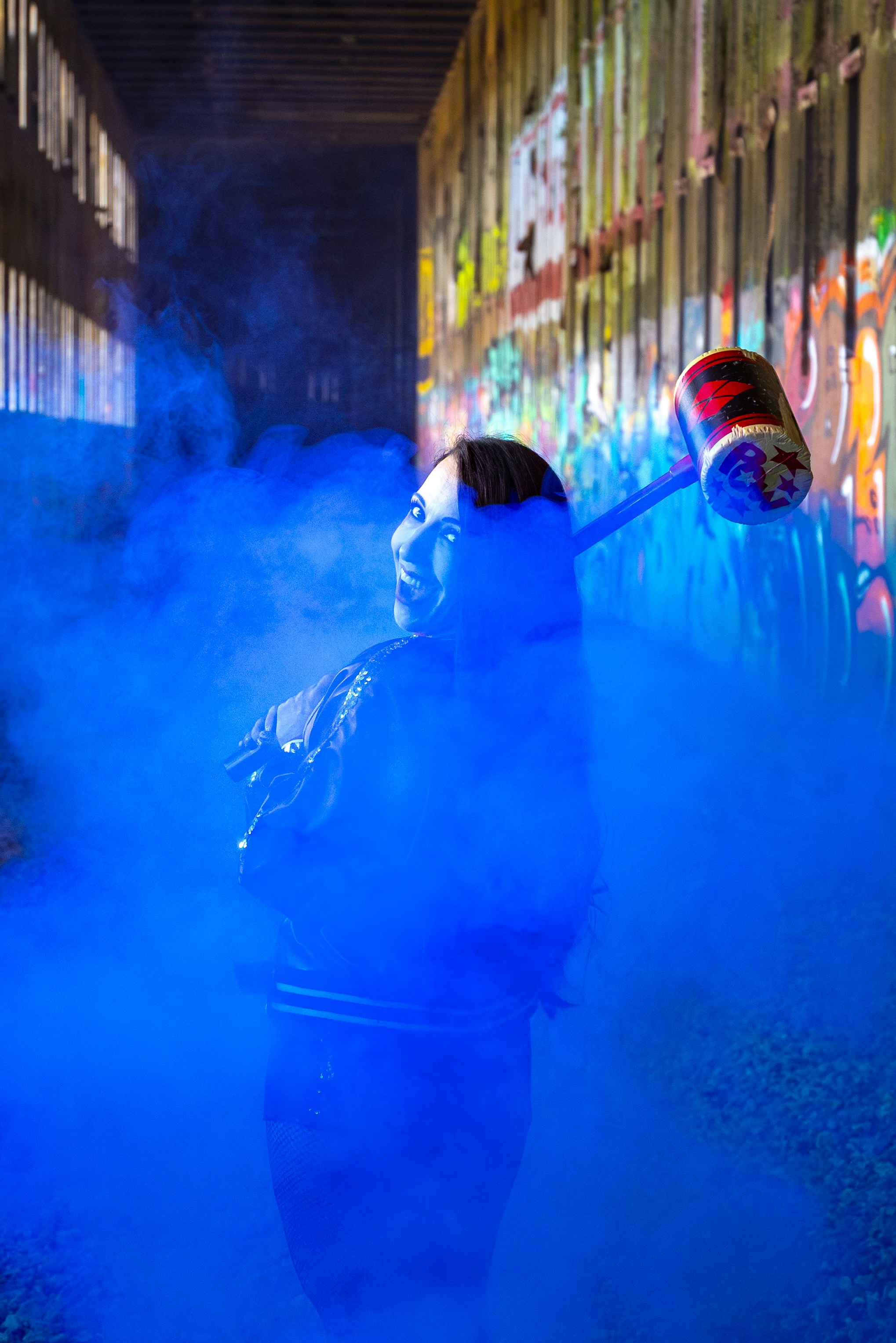 Wanita dengan palu dalam asap biru dan grafiti