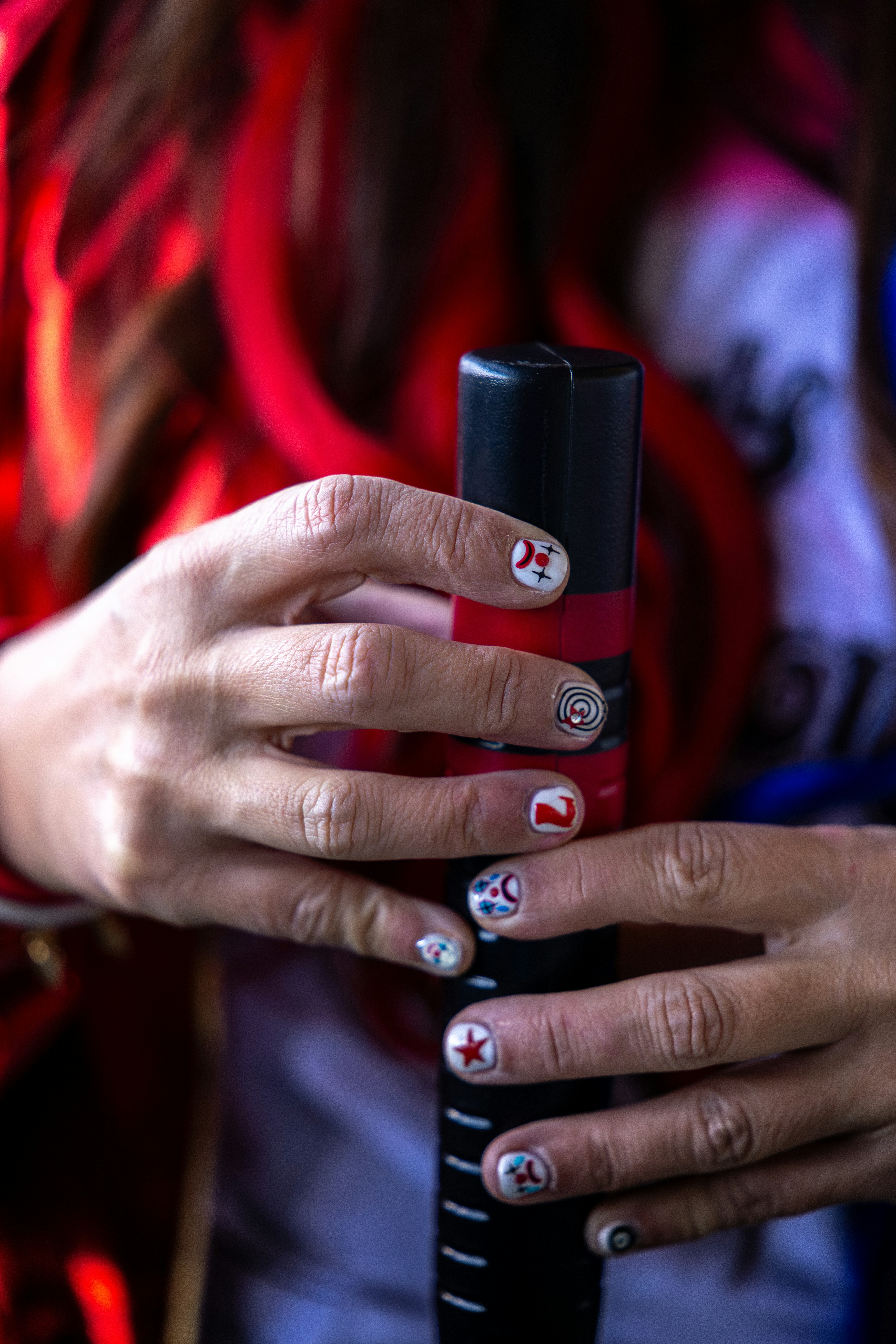 Woman's hands with painted nails holding a black cylinder