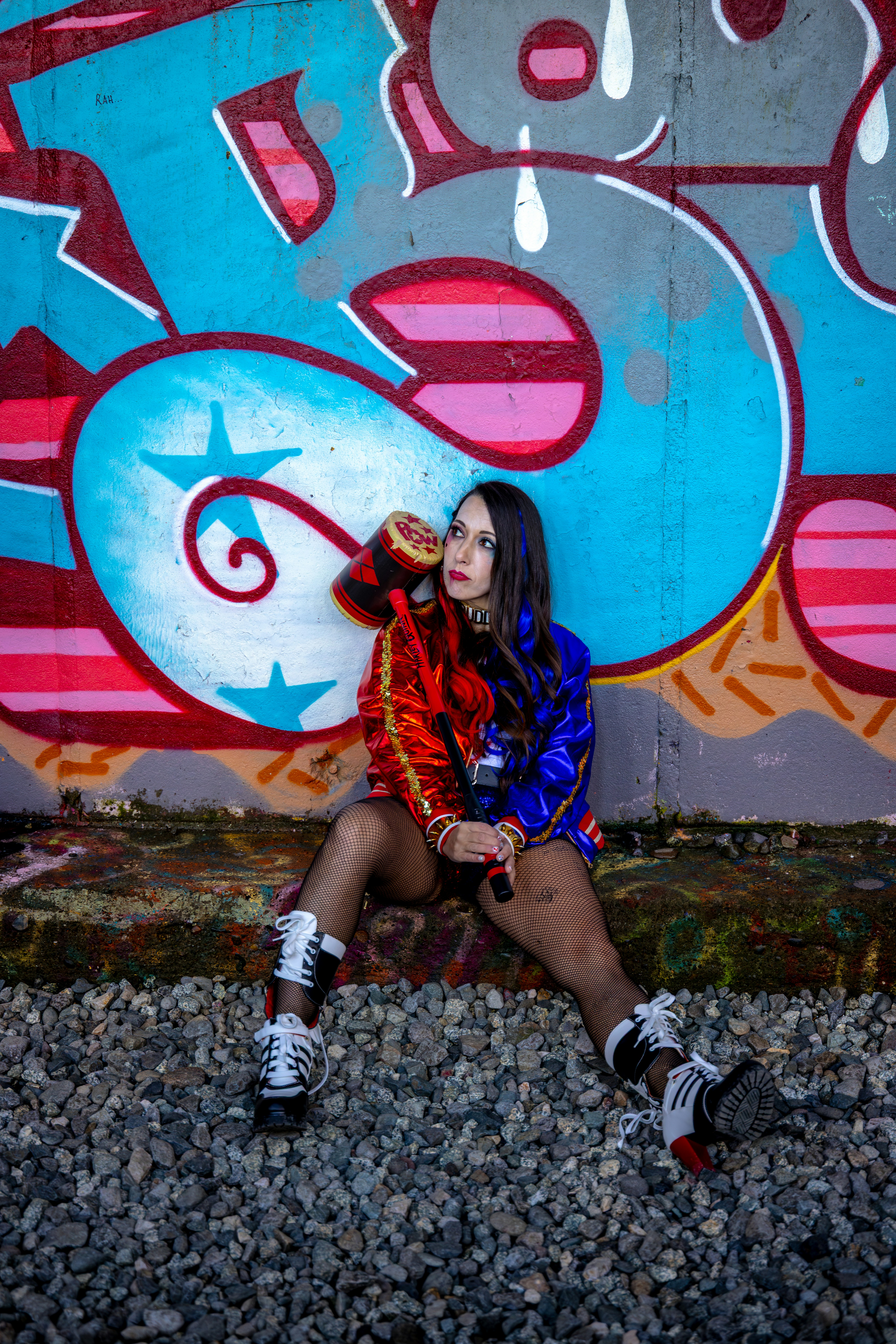 カラフルなジャケットを着た女性が落書きの壁に向かってポーズをとる