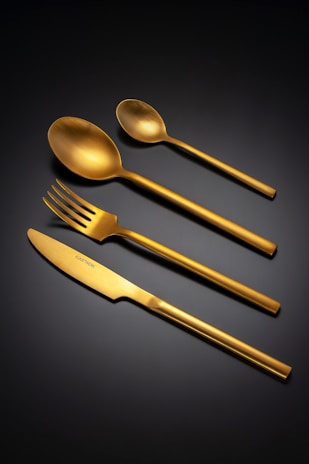 Golden cutlery set arranged on a dark background