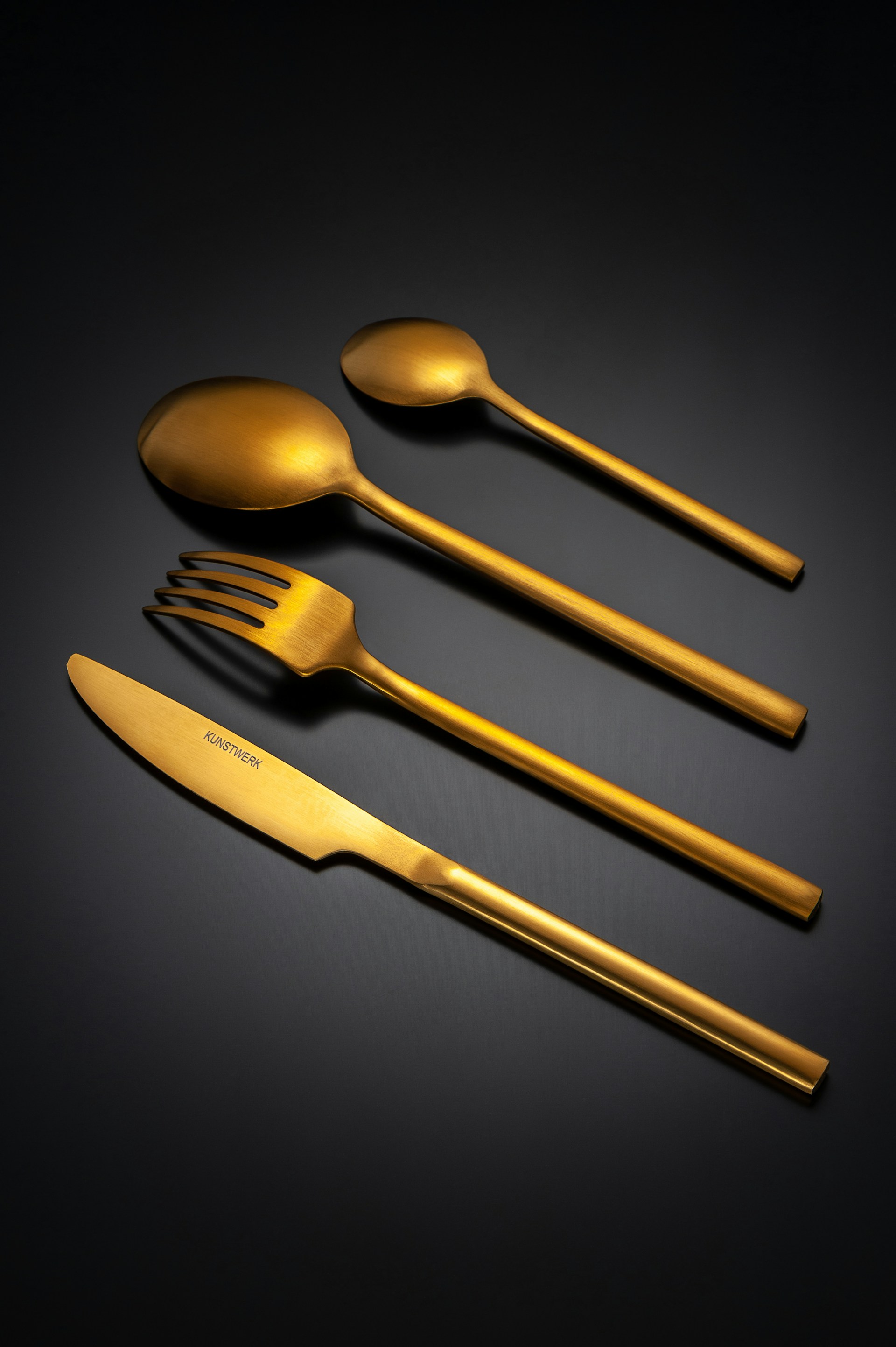 Set of four gold cutlery pieces on black background