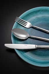 Silverware on a blue plate against a dark background.