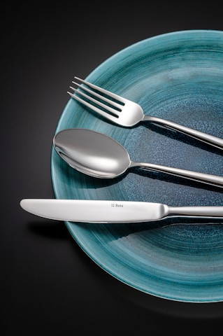 Silverware on a blue plate against a dark background.