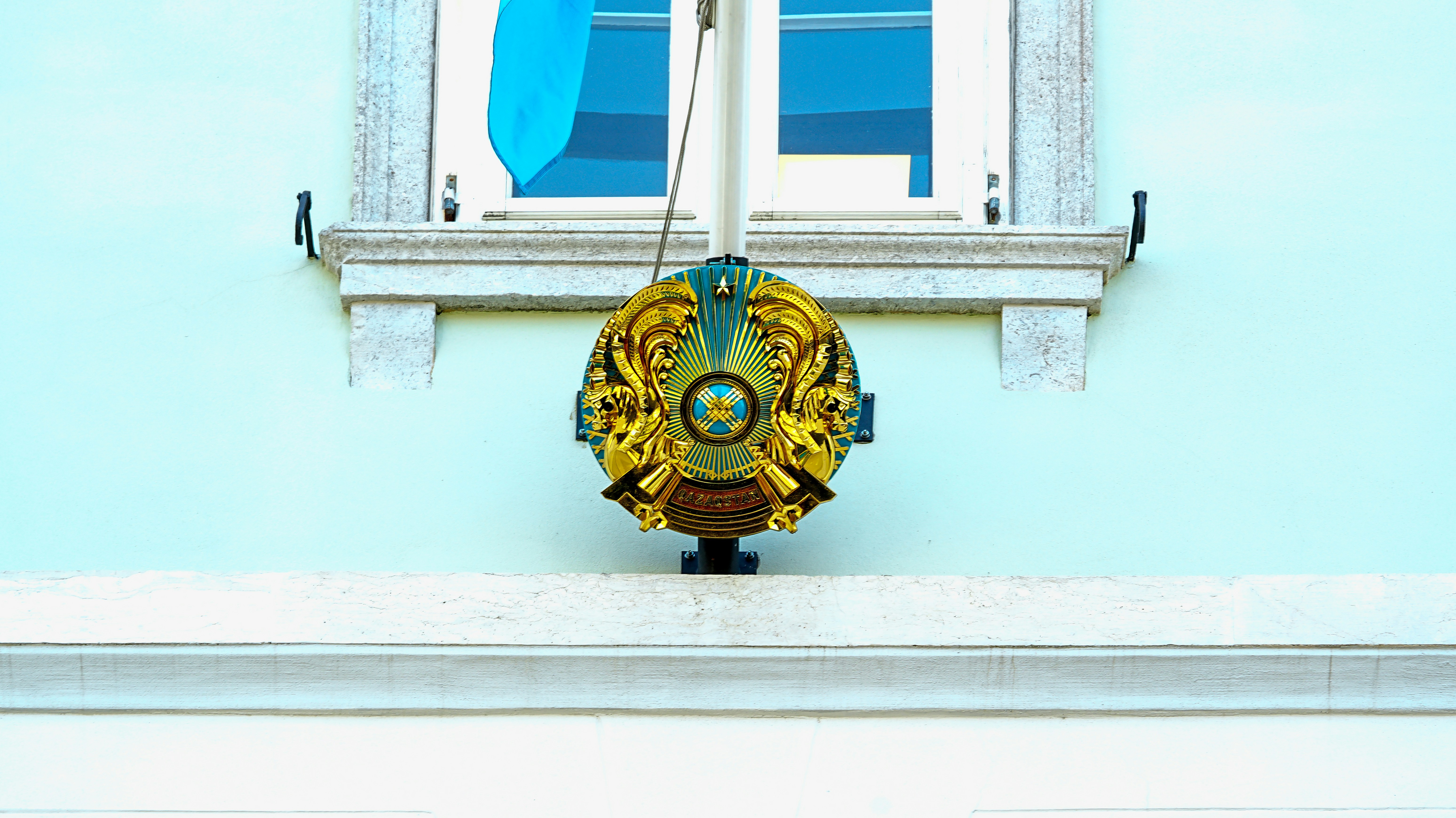 Cresta dorada ornamentada montada en una pared azul claro.