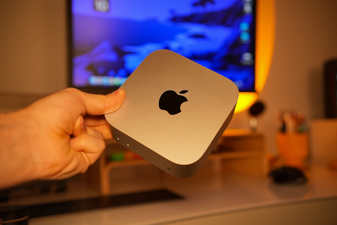 Hand holding a small silver Apple computer