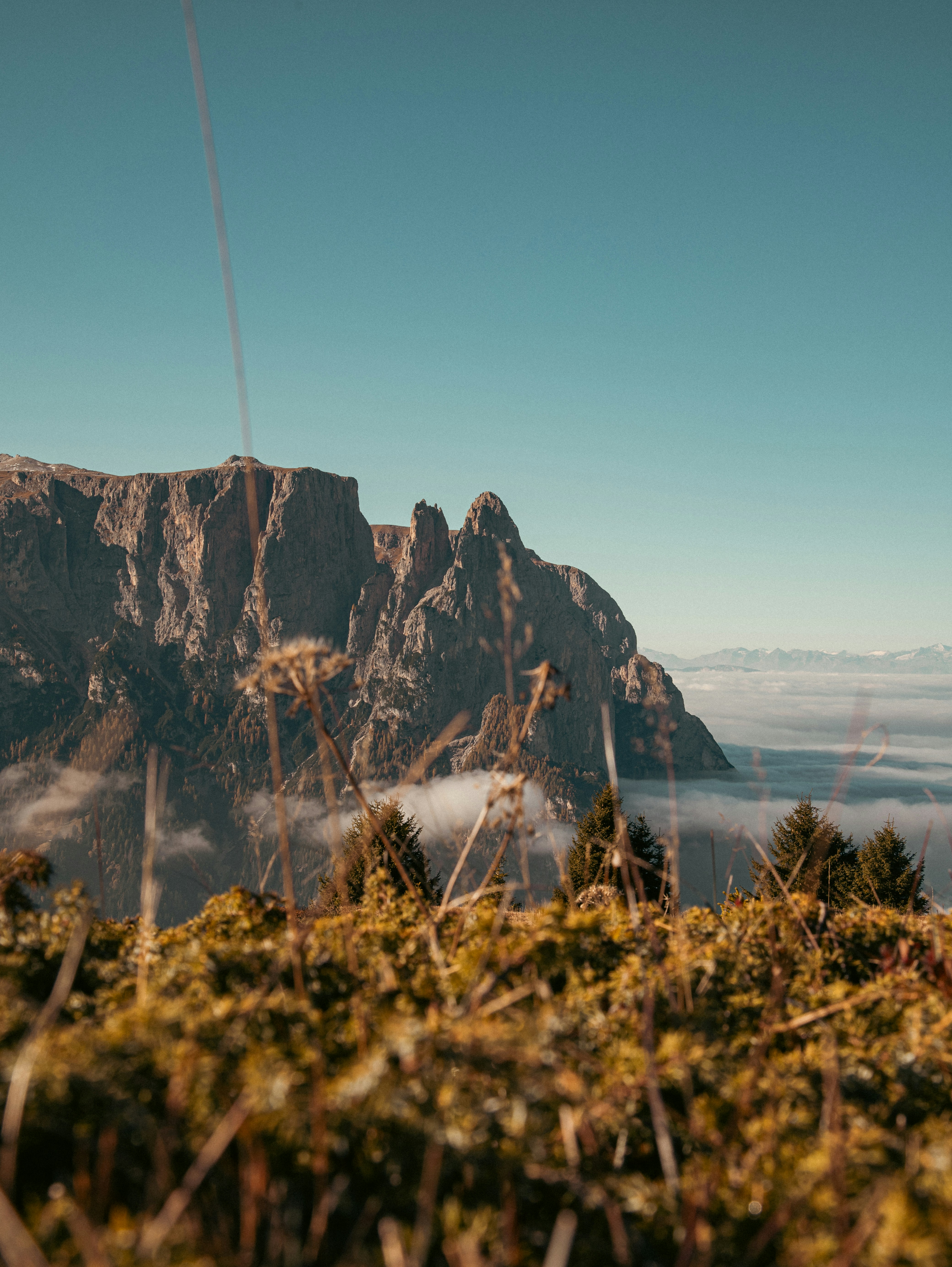 Majestic mountain range above clouds under clear sky.