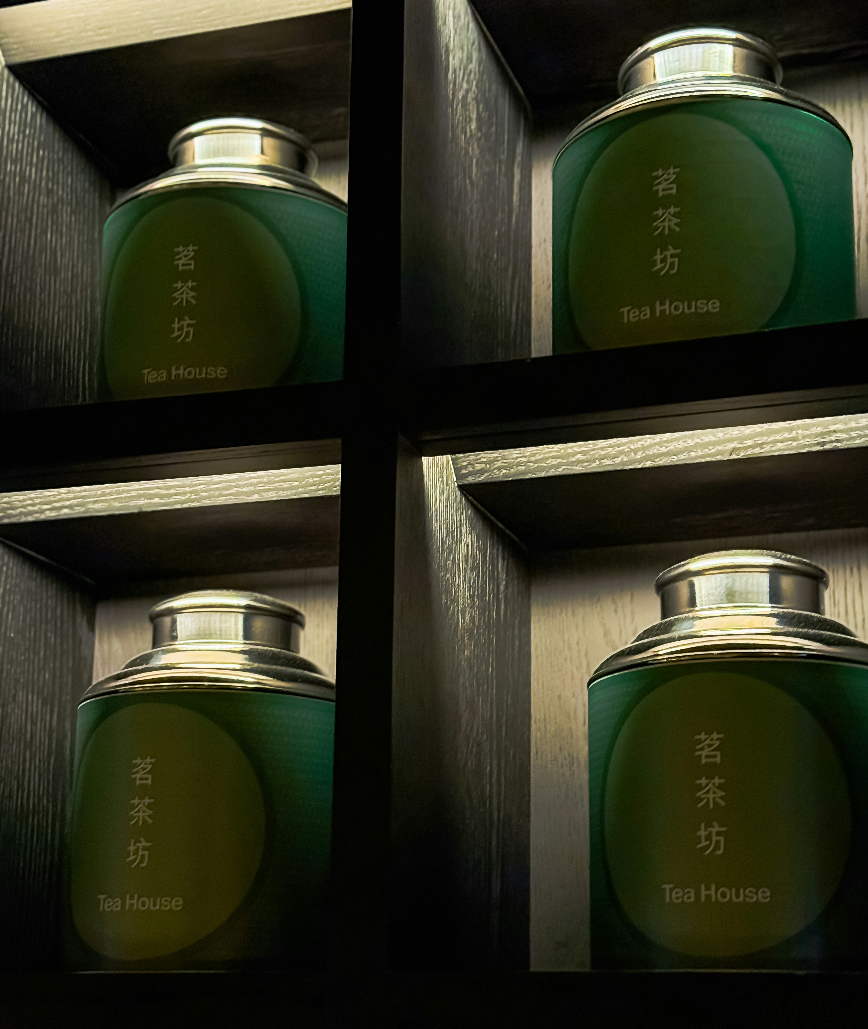 Four green tea canisters in wooden shelves