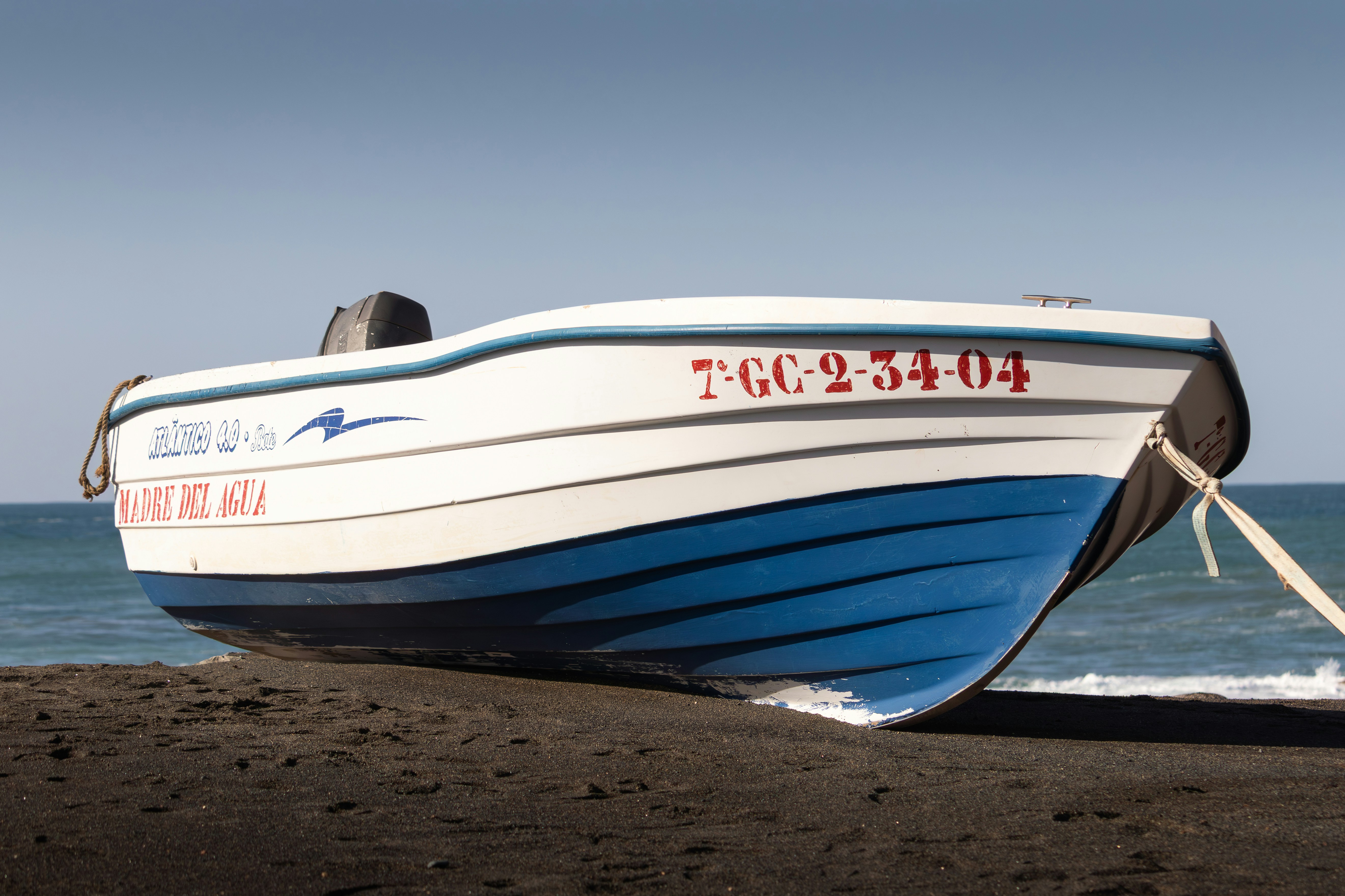 Ein kleines Boot ruht an einem dunklen Sandstrand.