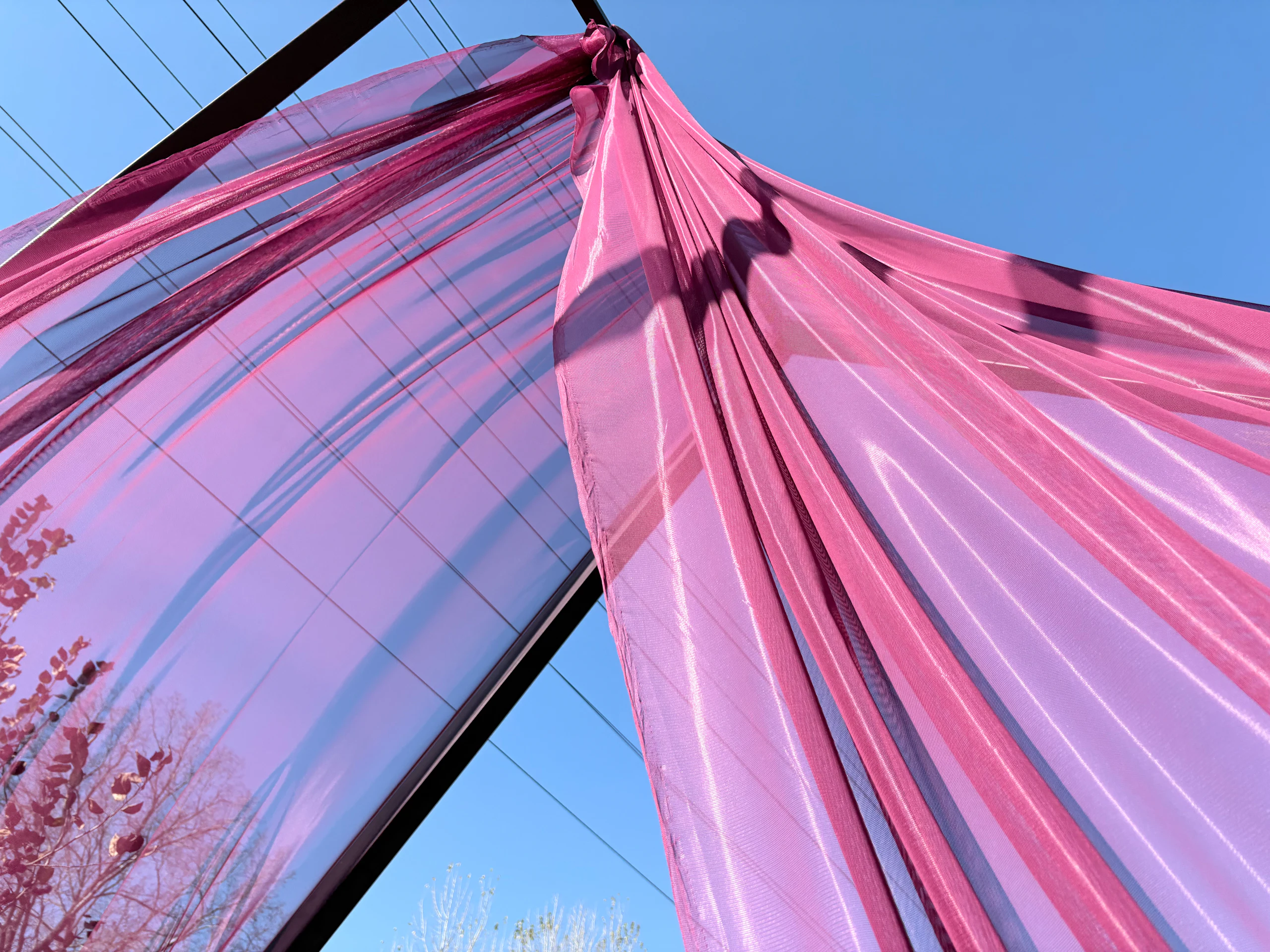 Pink fabric draping gathered against a clear blue sky