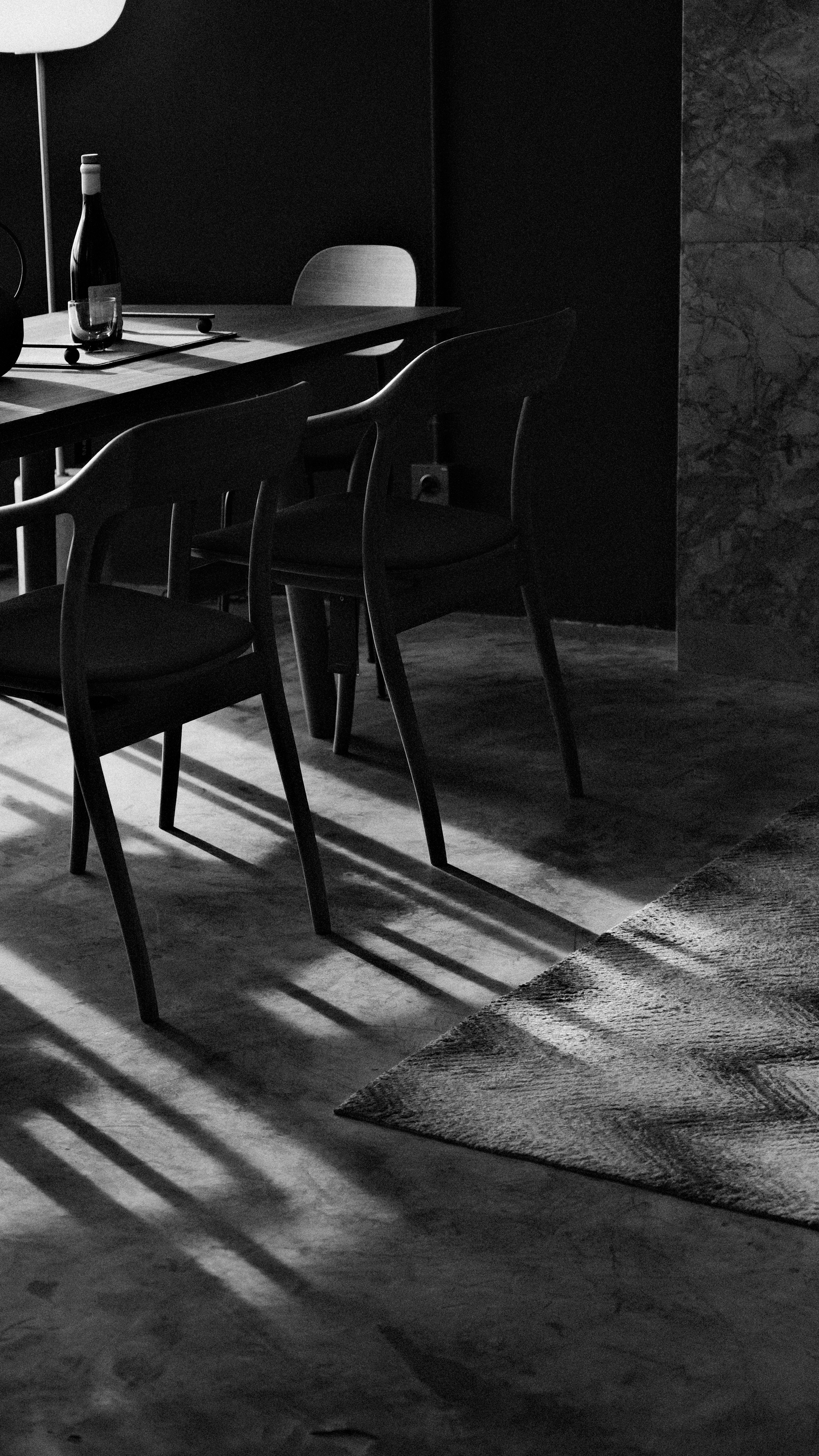Dining chairs cast long shadows on a rug.