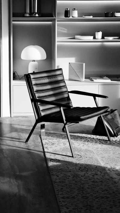 A modern black leather chair in a sunlit room.