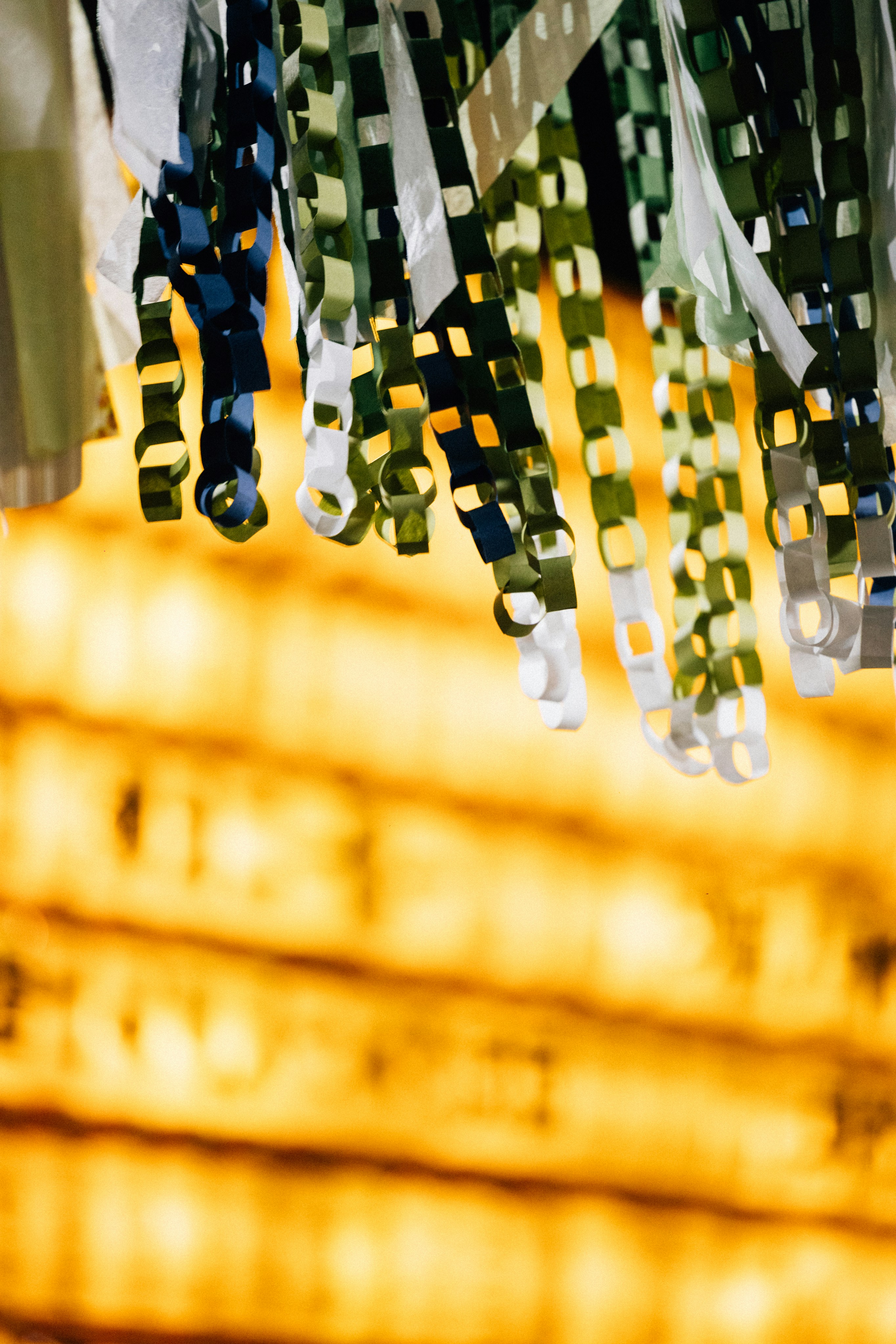 ぼやけた黄色の背景にぶら下がるカラフルな紙のストリーマー