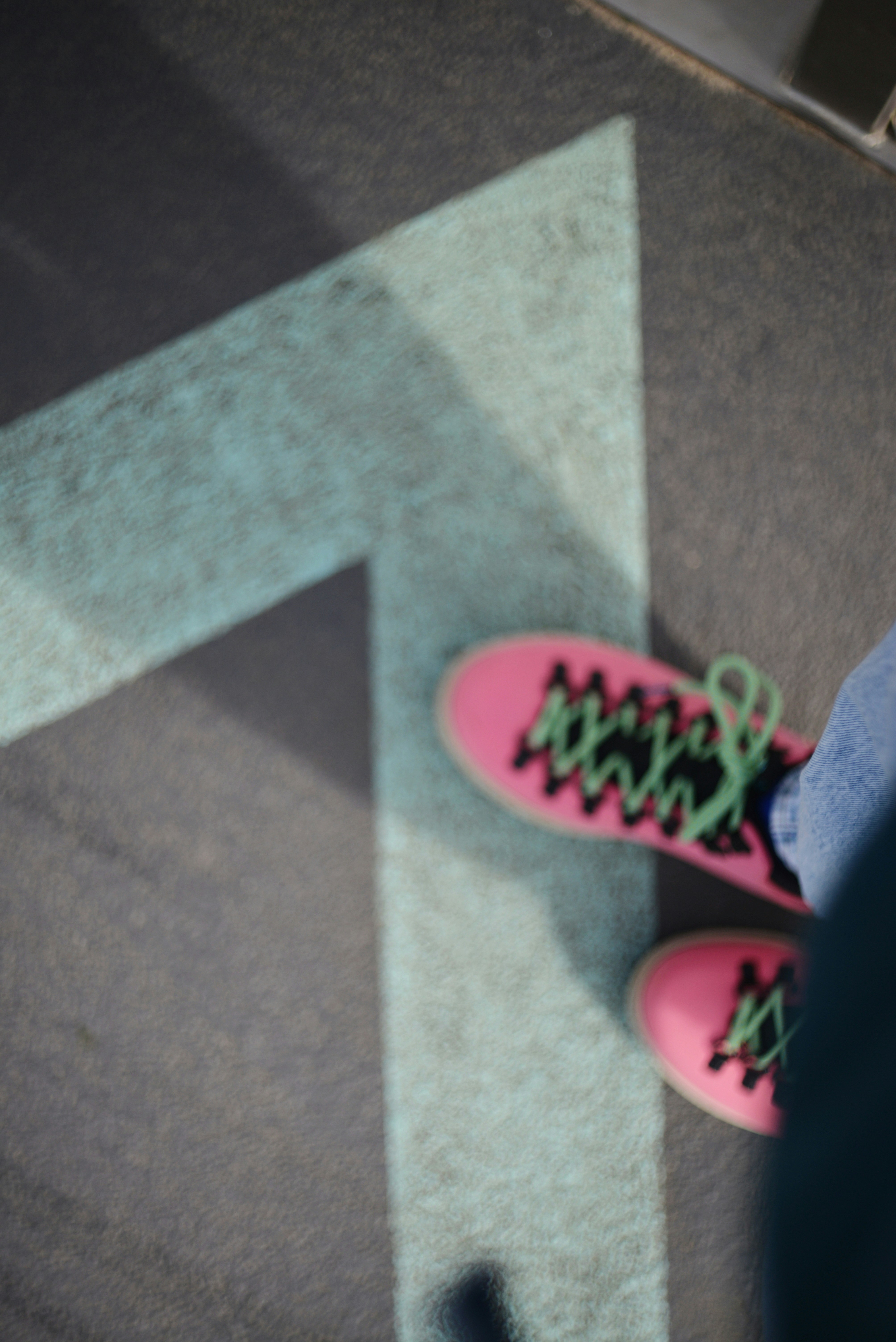 Rosa Schuhe mit grünen Schnürsenkeln auf dem Boden.