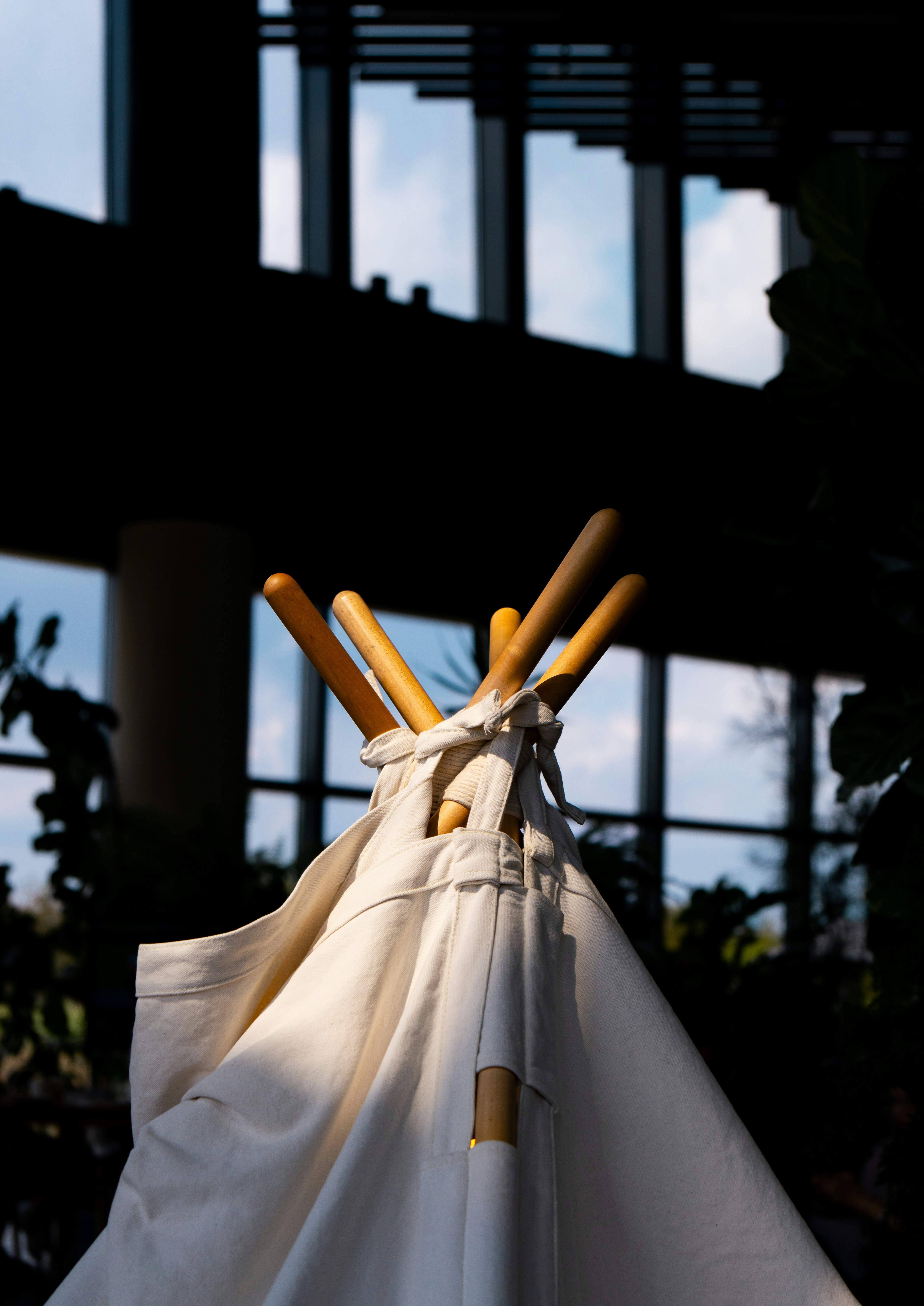 White teepee tent with wooden poles indoors.