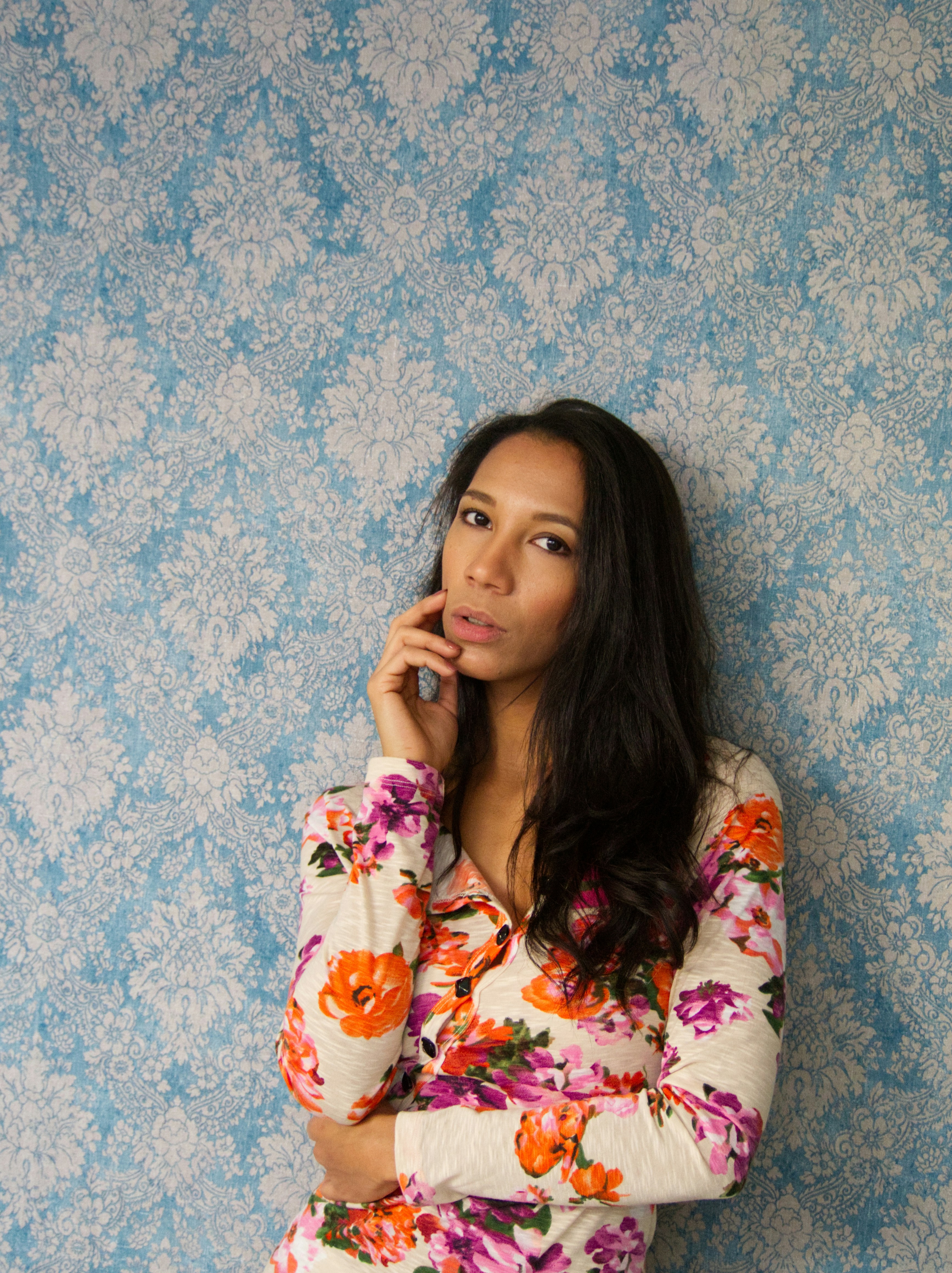 Mujer con camisa floral contra papel pintado azul estampado