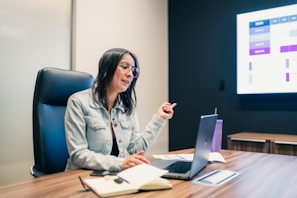 Woman presenting data on a laptop and screen.