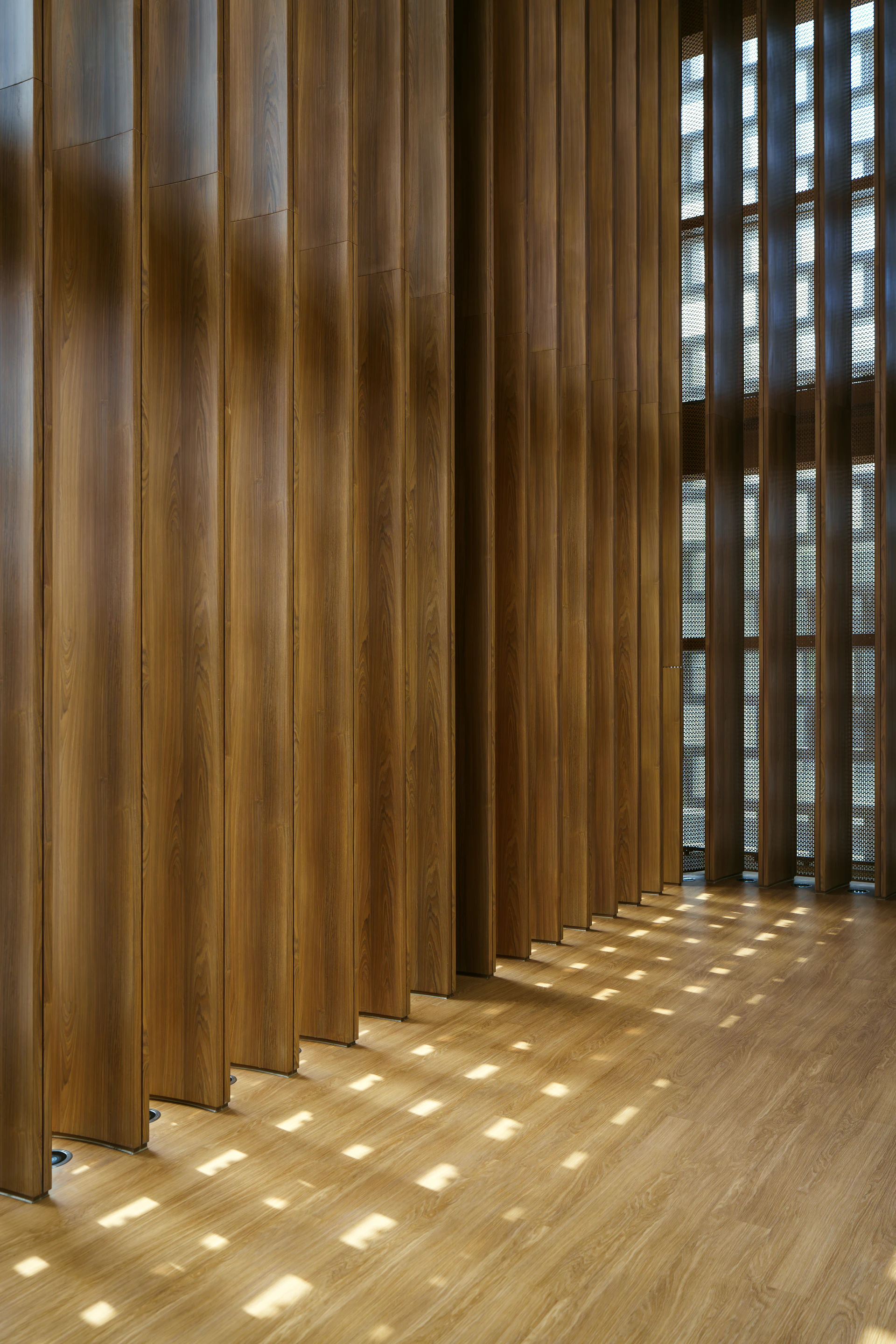 Wooden slats create patterns of light on floor.