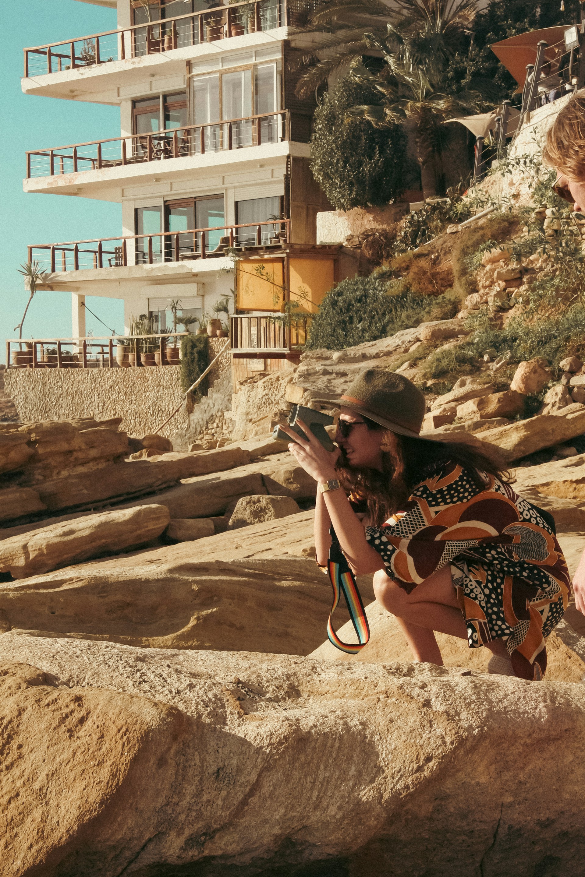Woman crouching on rocks taking a photo