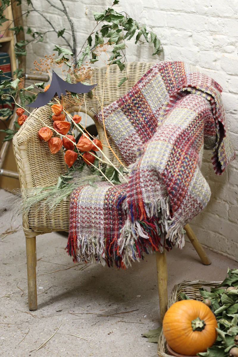 Wicker chair with a woven blanket and autumn decorations