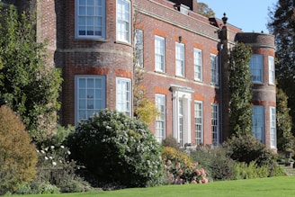 Grand brick manor house with lush gardens and trees