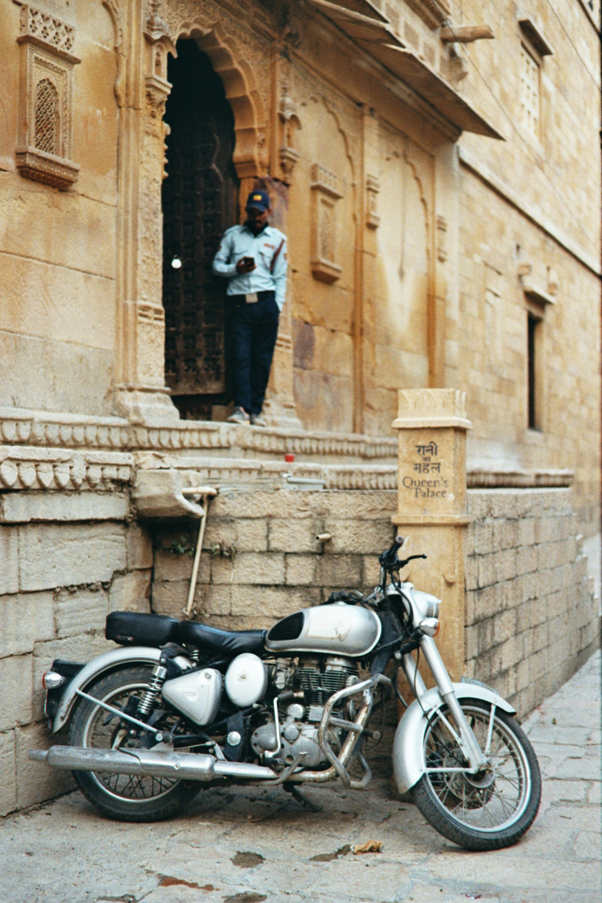 Man in uniform stands by motorcycle outside building
