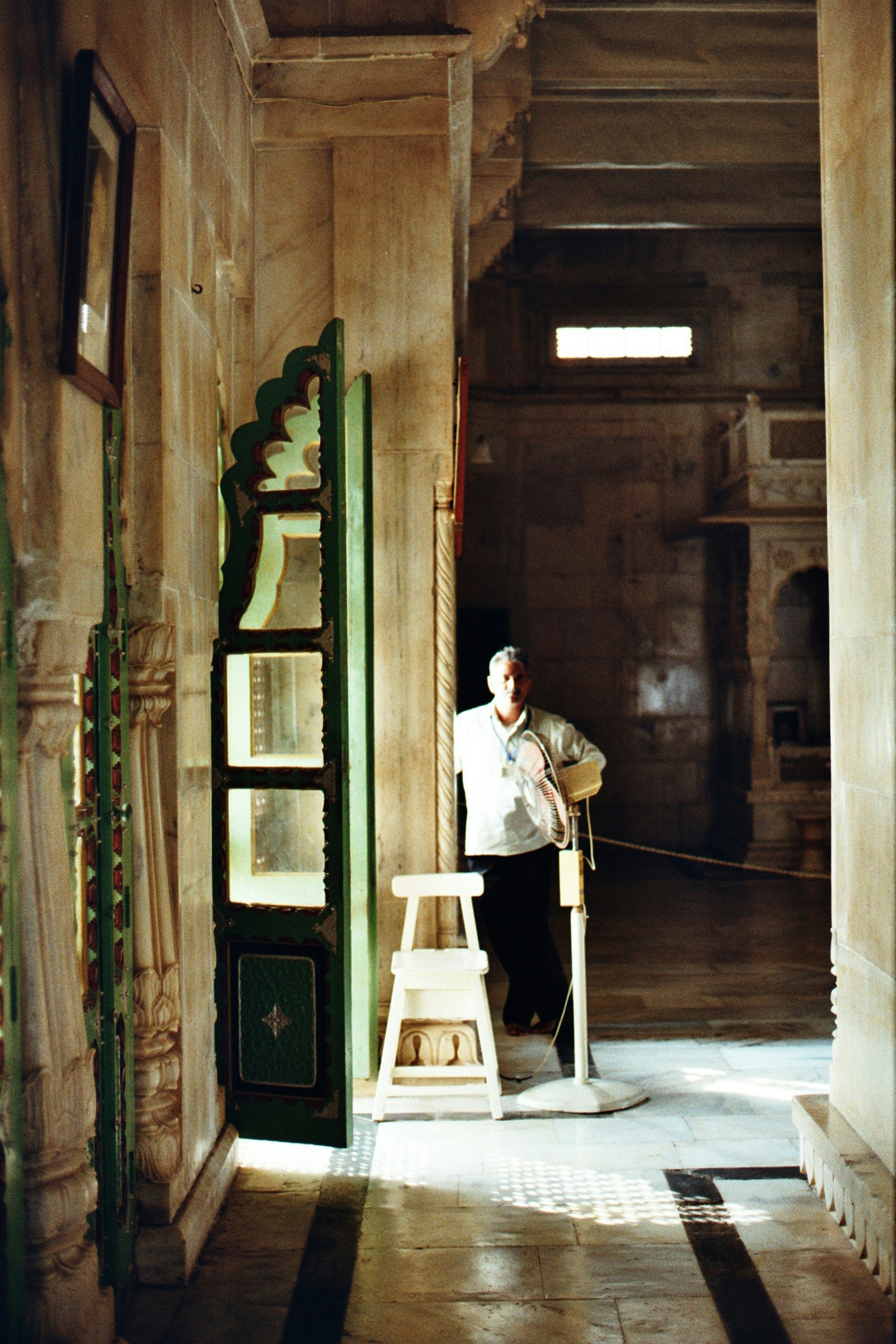 Man standing in a hallway with ornate green door.